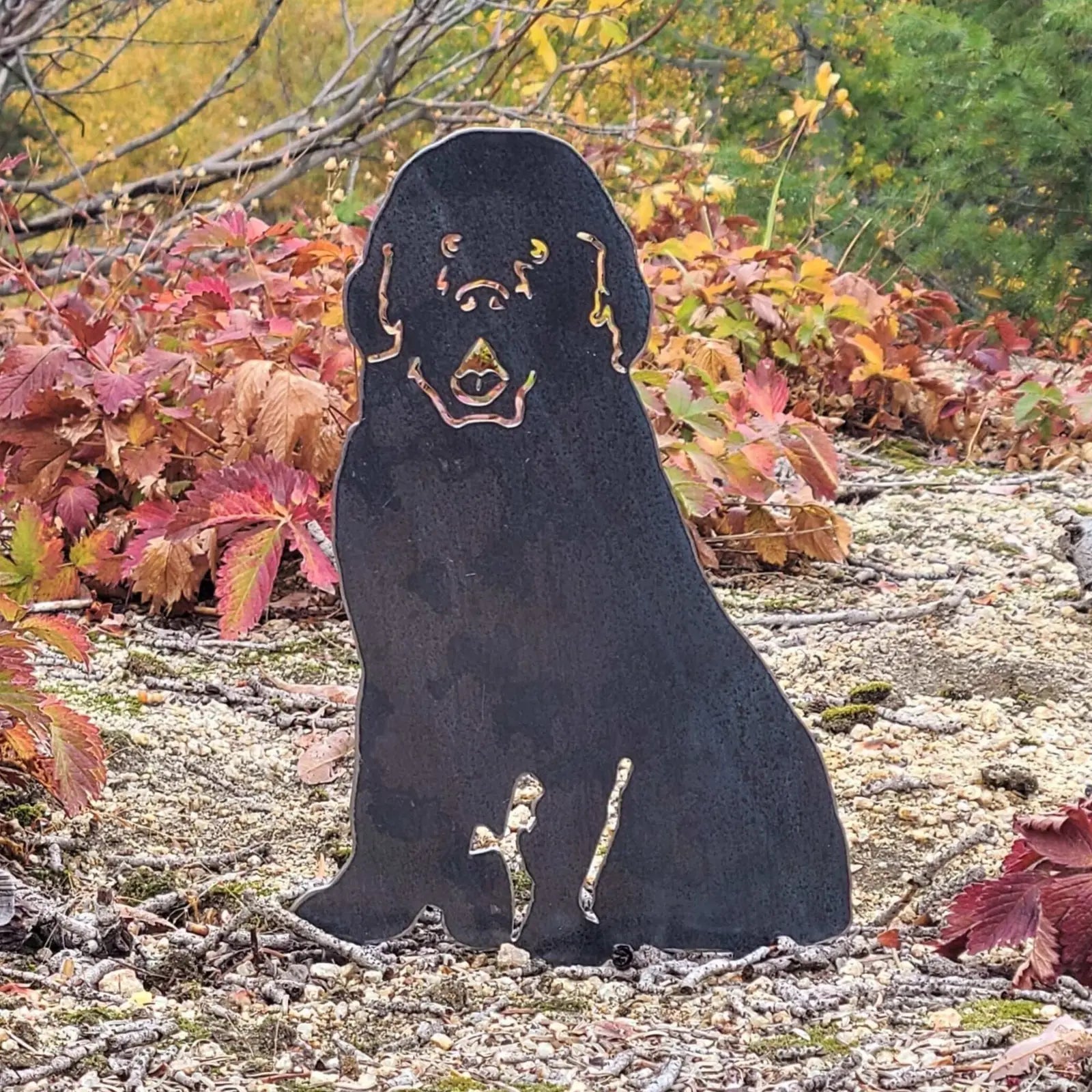 Black metal silhouette of a Newfoundland dog surrounded by autumn foliage, showcasing durable outdoor decor.