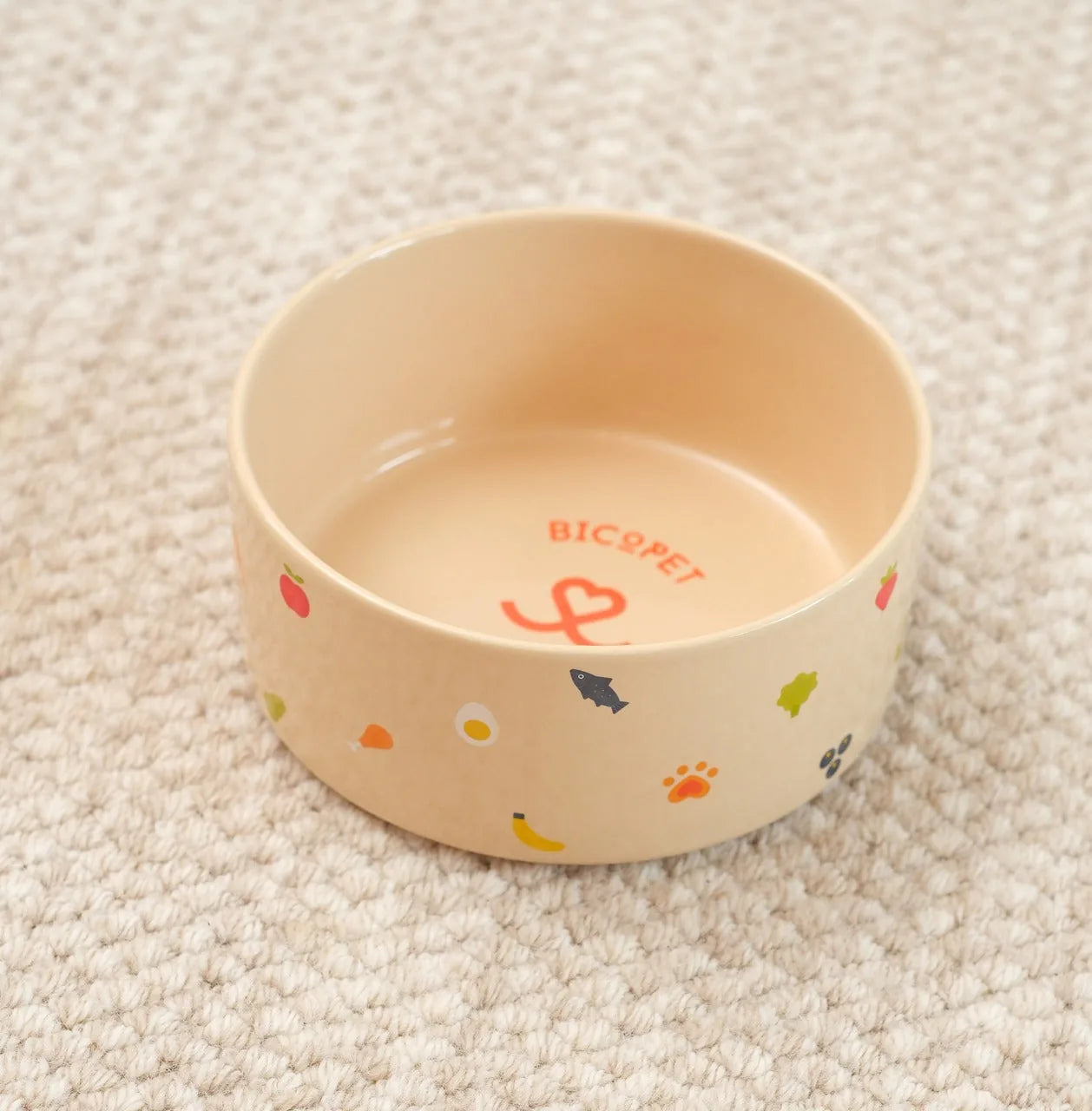 Cream-colored ceramic pet bowl with colorful food prints, a non-slip base, and a durable design.
