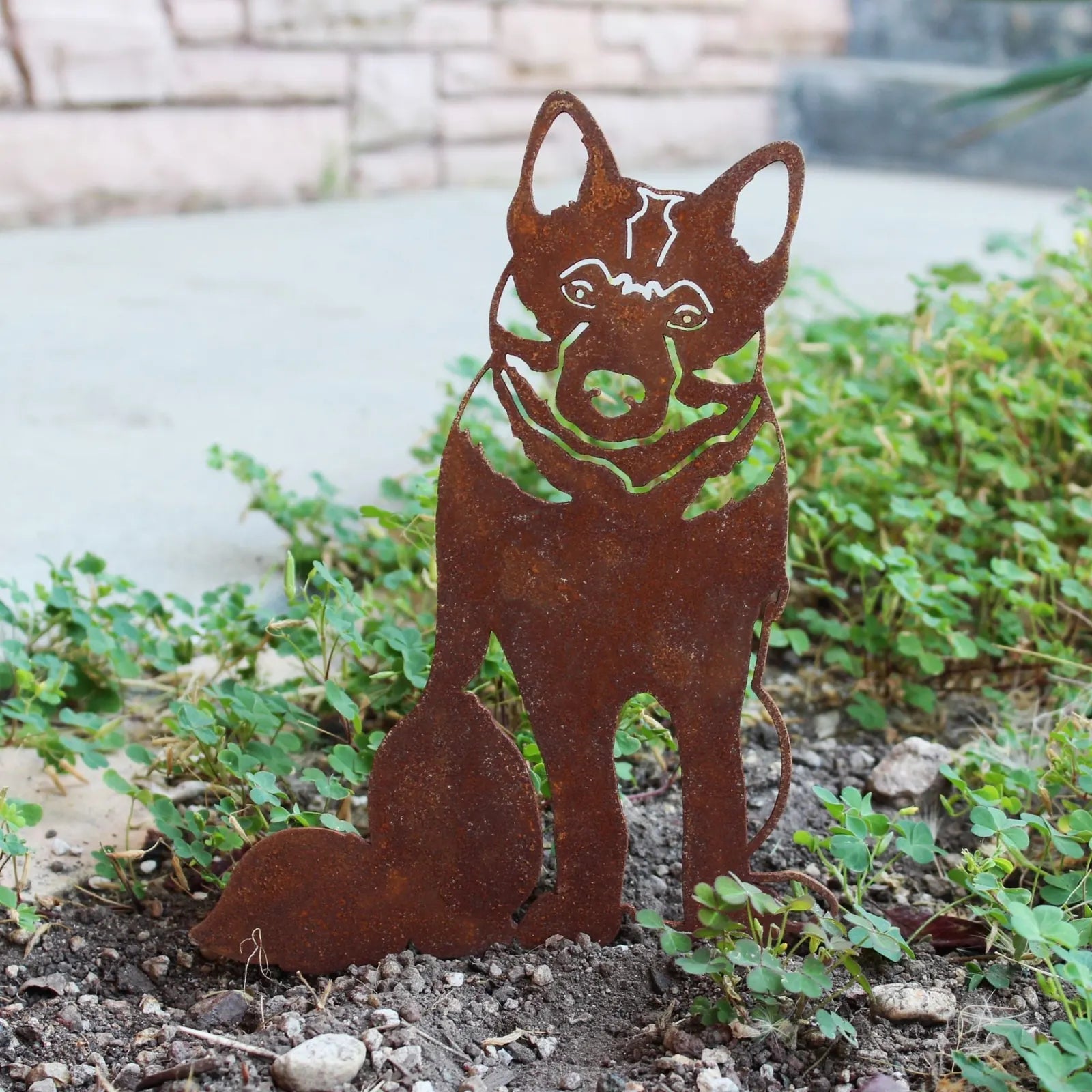 Rusty metal silhouette of a Norwegian Elkhound sitting in greenery, showcasing a durable outdoor décor design.