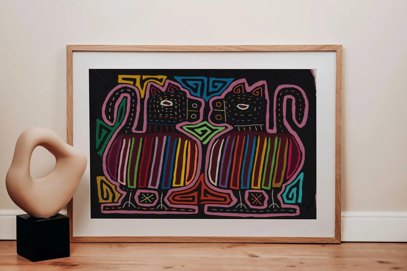 Colorful hand-stitched Mola depicting two stylized dogs, surrounded by geometric patterns on a black background.