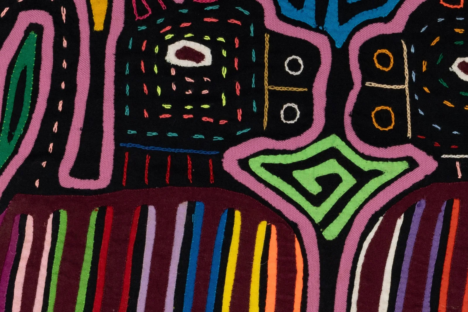 Hand-stitched Mola featuring vibrant multicolored geometric patterns on a black background.