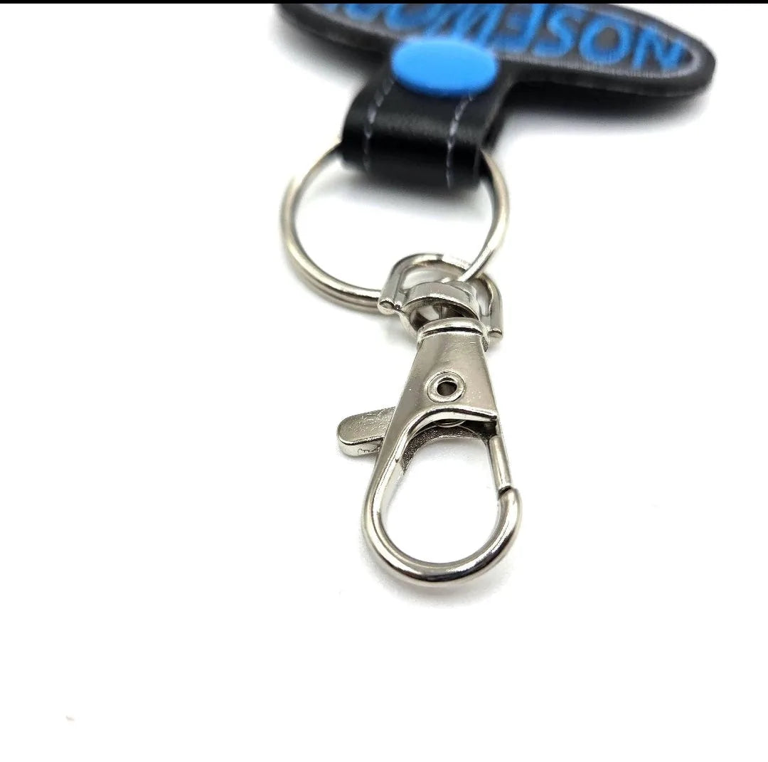 Close-up of a silver swivel clip and key ring attached to a blue and black embroidered keychain for dog scent work.