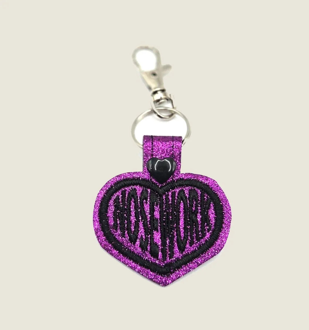 Embroidered purple heart keychain with "NOSE WORK" in black, featuring a swivel clip and shiny black heart detail.
