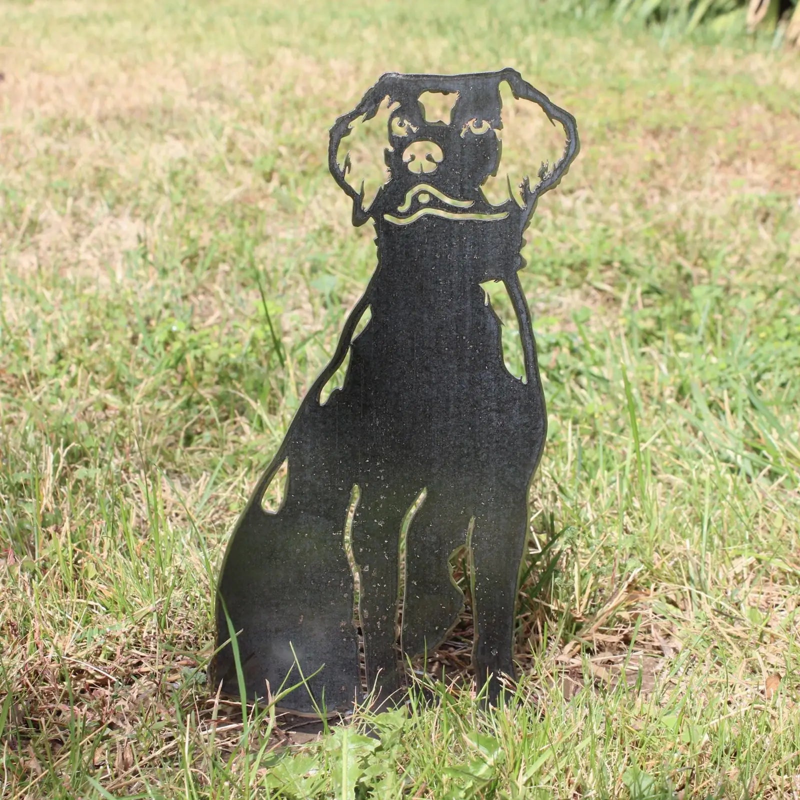 Black metal silhouette of a Nova Scotia Duck Tolling Retriever standing in grass, showcasing intricate cut-out details.