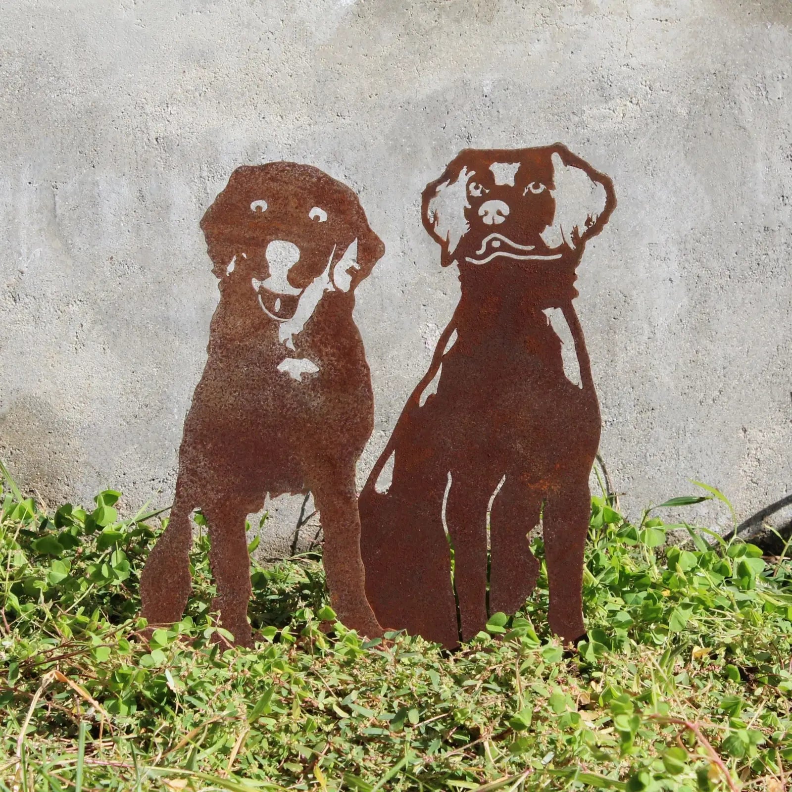 Rusty metal silhouette of two Nova Scotia Duck Tolling Retrievers, standing amidst green grass against a neutral background.