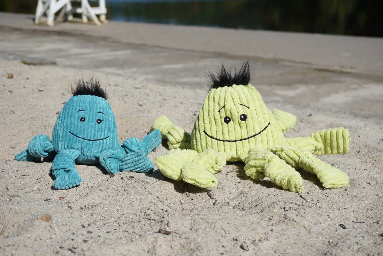 Plush Octavie the Octopus Knottie® dog toys in sea blue and octo green, featuring knotted limbs and cheerful faces on sand...