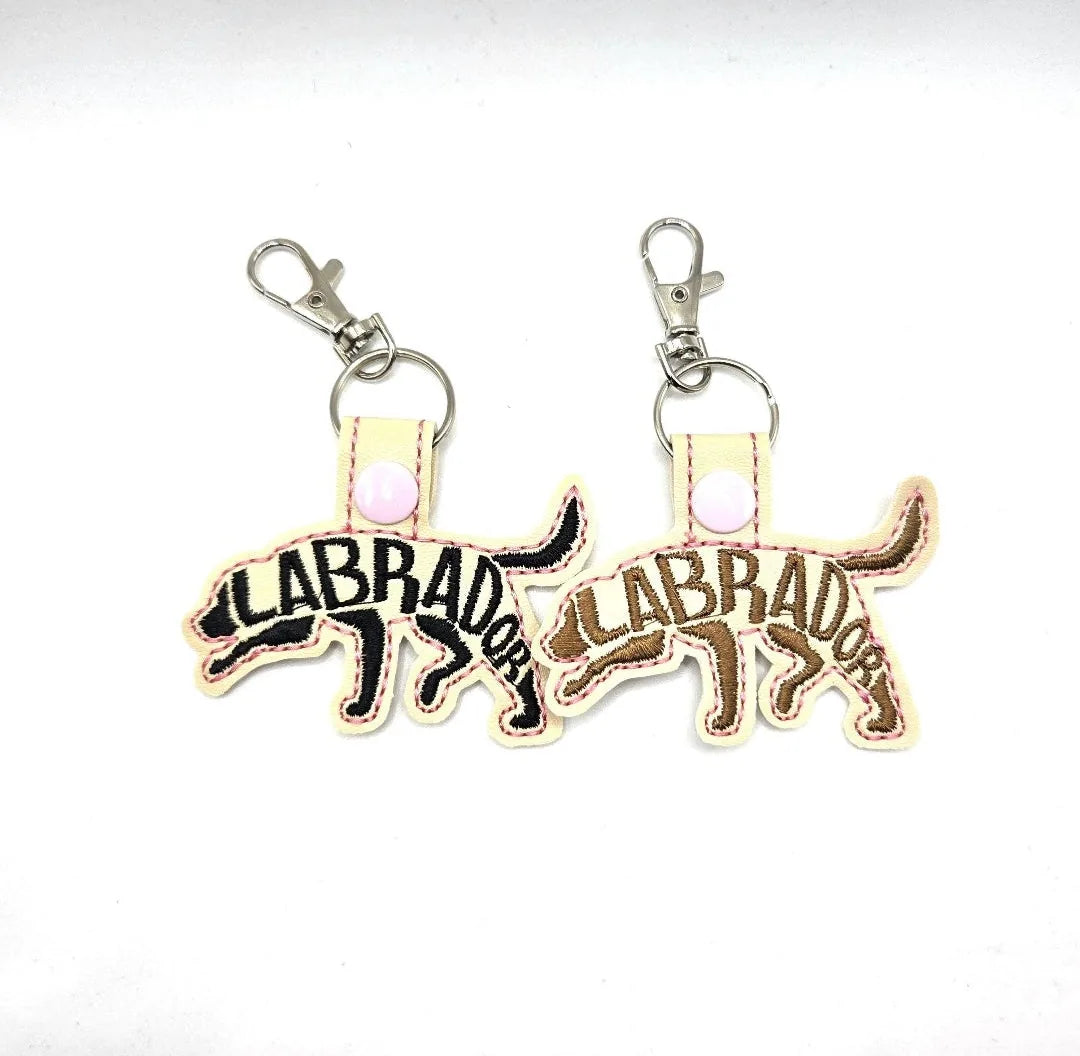 Embroidered Labrador Retriever keychain tabs in black and brown, featuring the word "LABRADOR" stitched across.