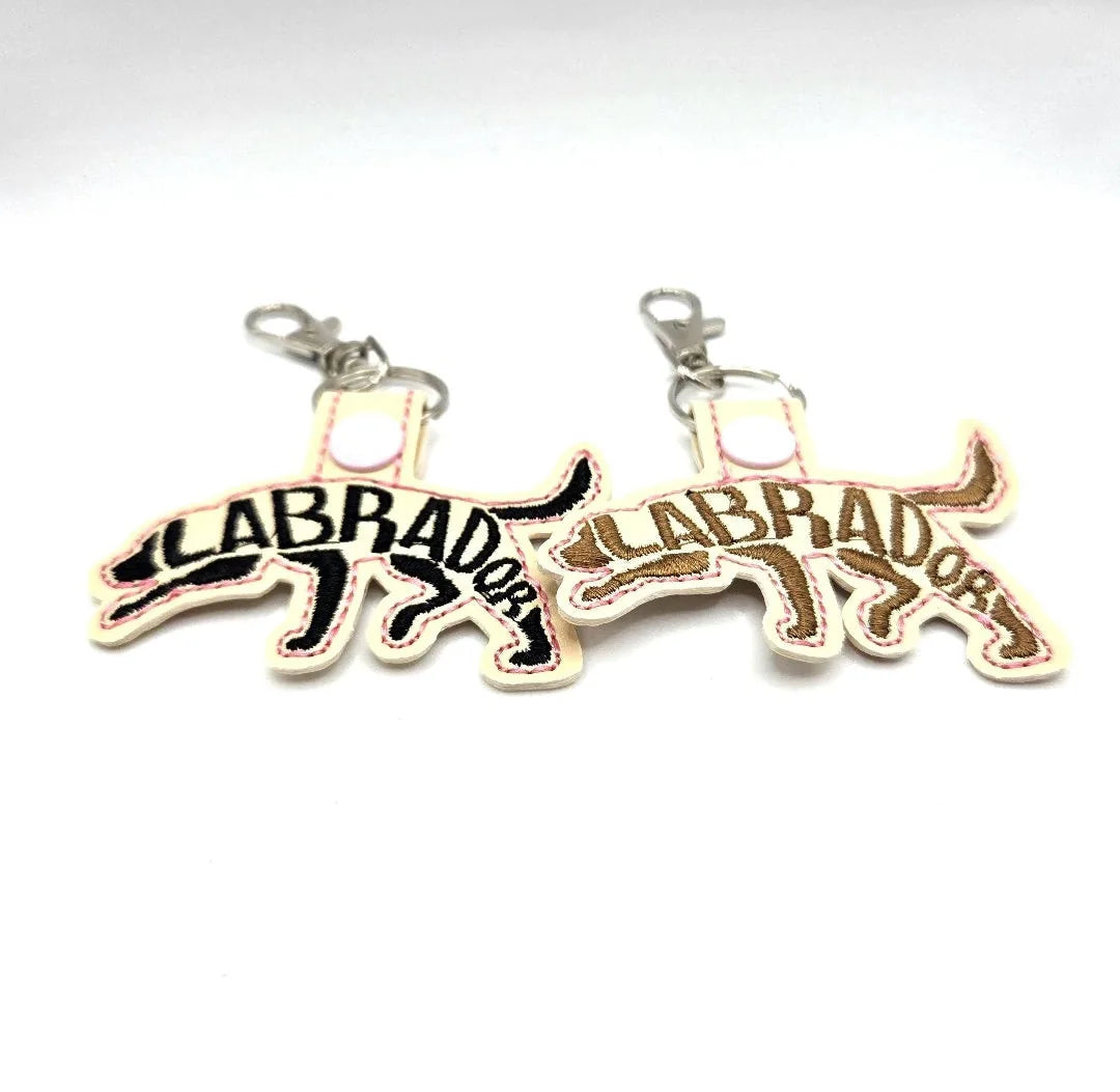 Embroidered Labrador Retriever keychains in black and brown, each with "LABRADOR" stitched across the body.
