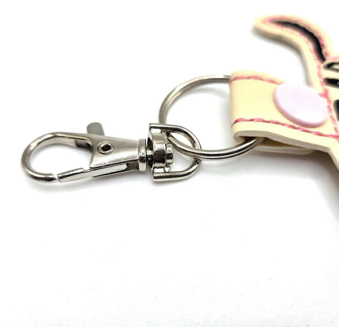 Swivel clip and keyring attachment of a Labrador Retriever keychain with a beige tab and pink accent button.