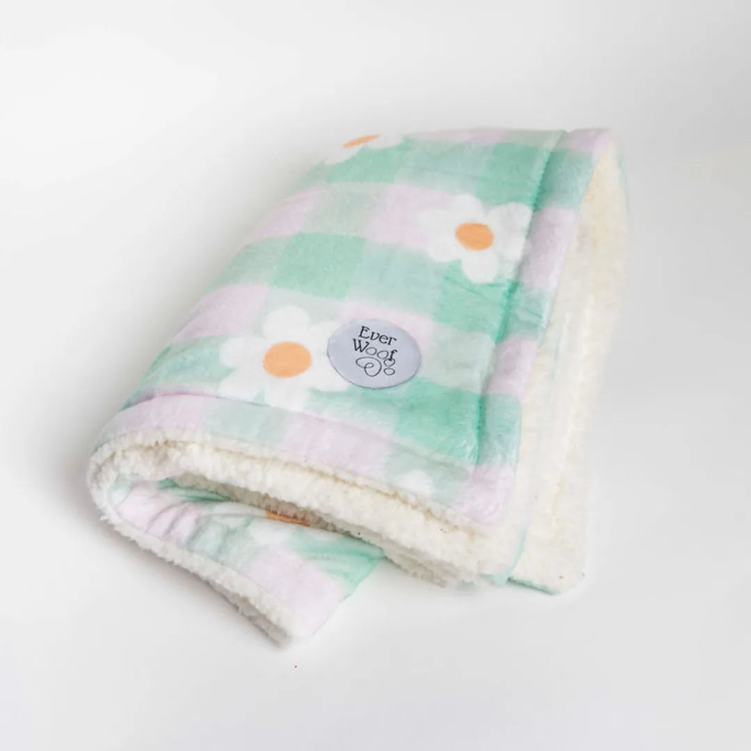 Soft, double-sided dog blanket featuring a green and pastel floral pattern with cream sherpa lining, perfect for cozying up.