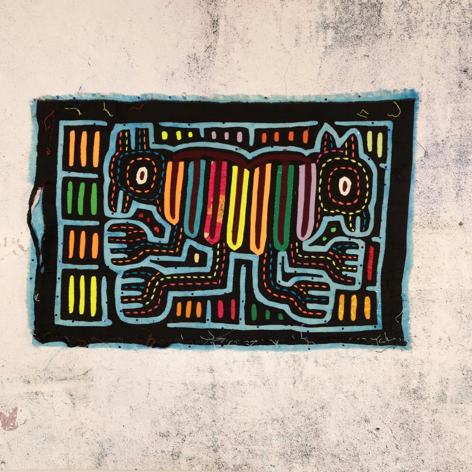Optical illusion tapestry featuring two colorful, hand-stitched dogs against a black background, showcasing traditional Mo...