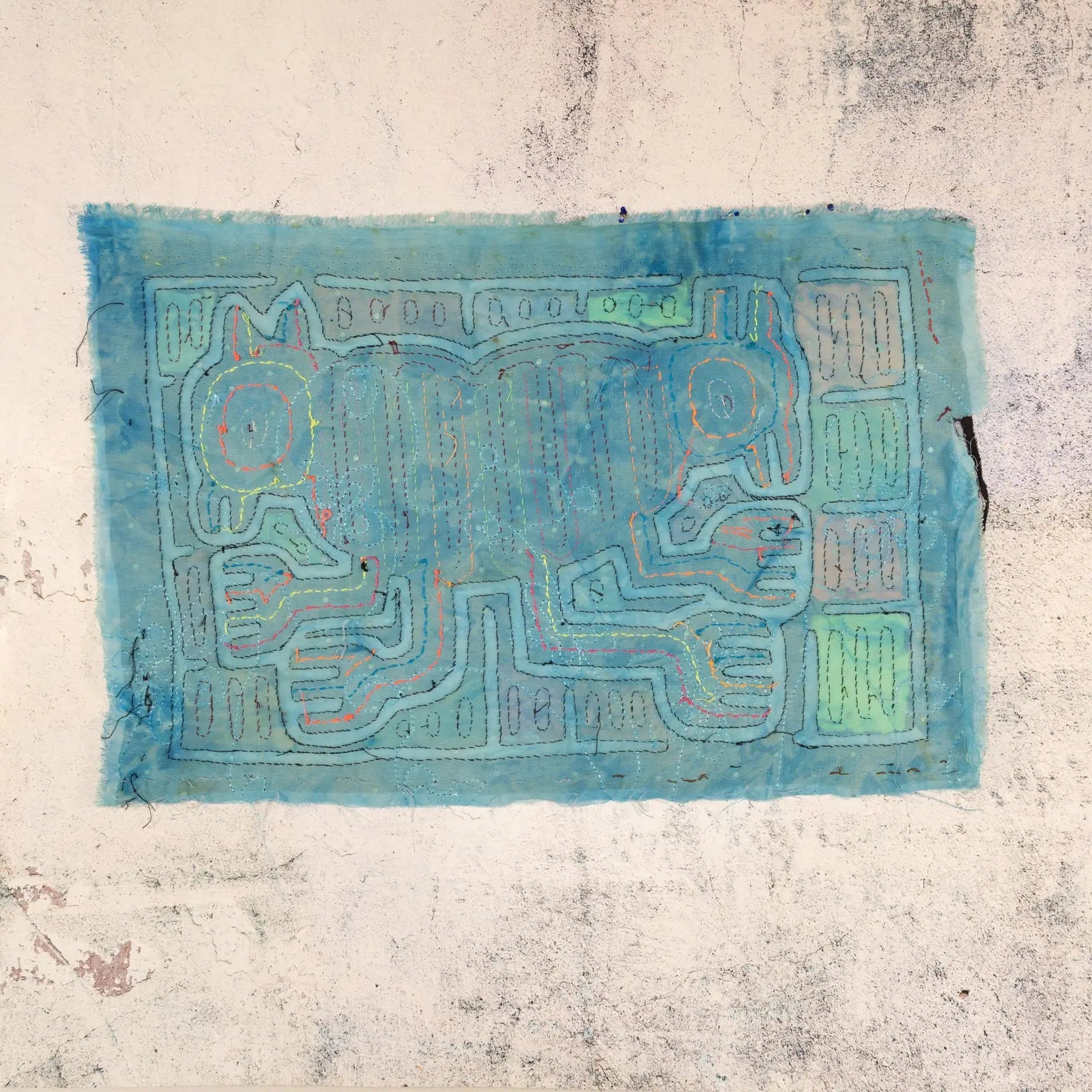 Hand-stitched blue Mola textile featuring an optical illusion design with two dogs, showcasing vibrant stitching details.