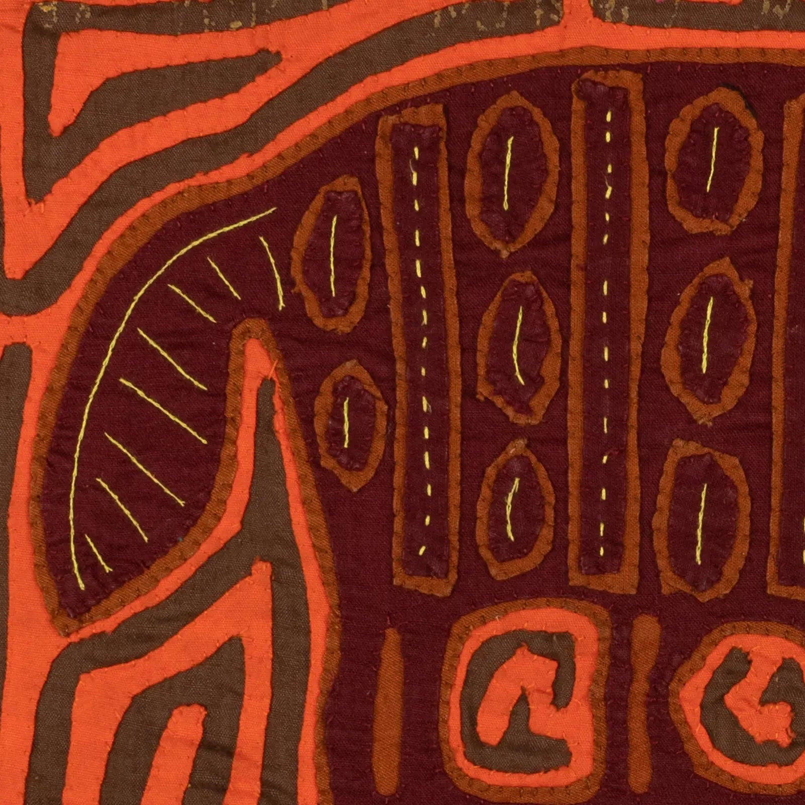 Orange and brown hand-stitched Mola tapestry featuring intricate patterns and designs inspired by rainforest wildlife.