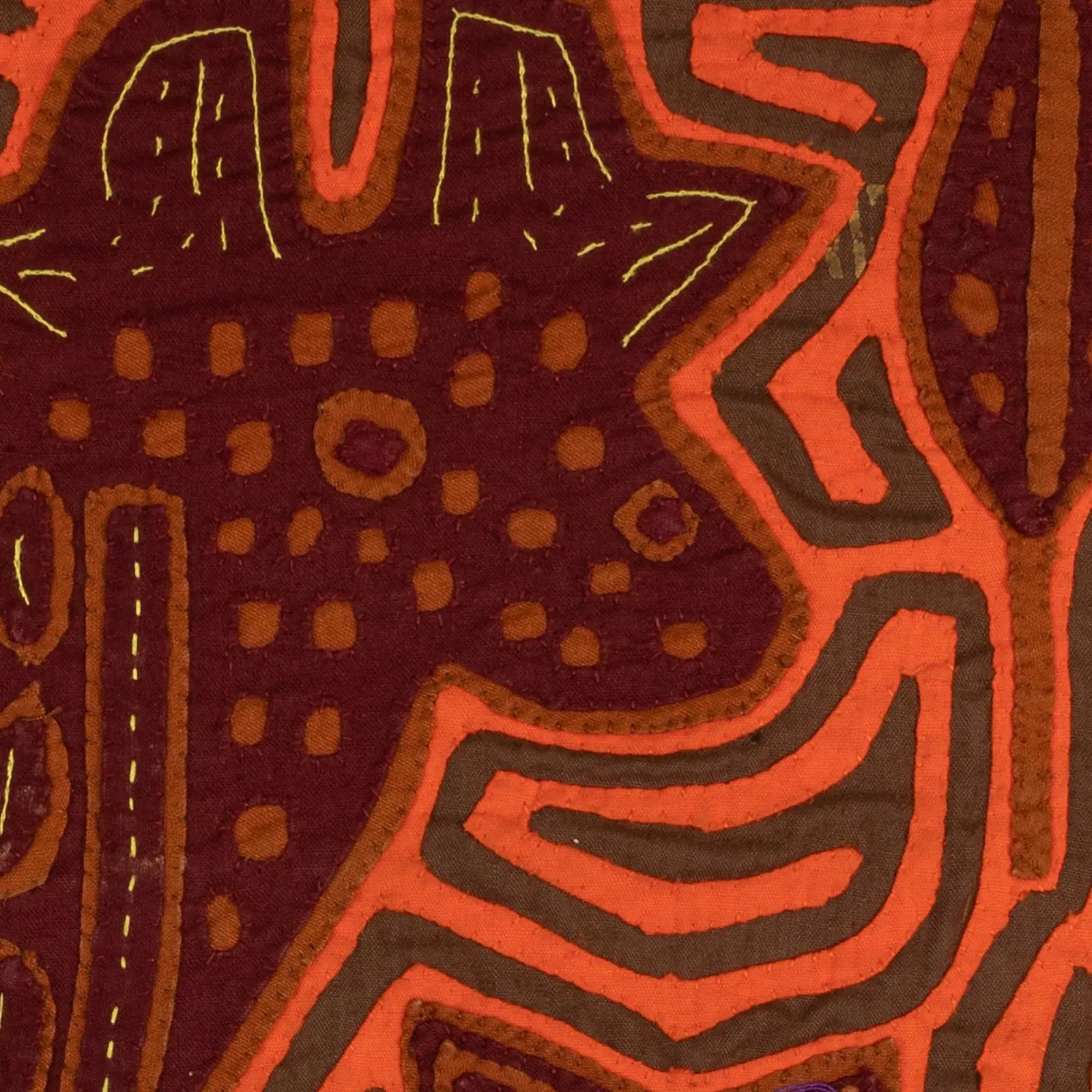 Hand-stitched orange and brown pattern featuring a puppy silhouette with geometric designs on a textile tapestry.