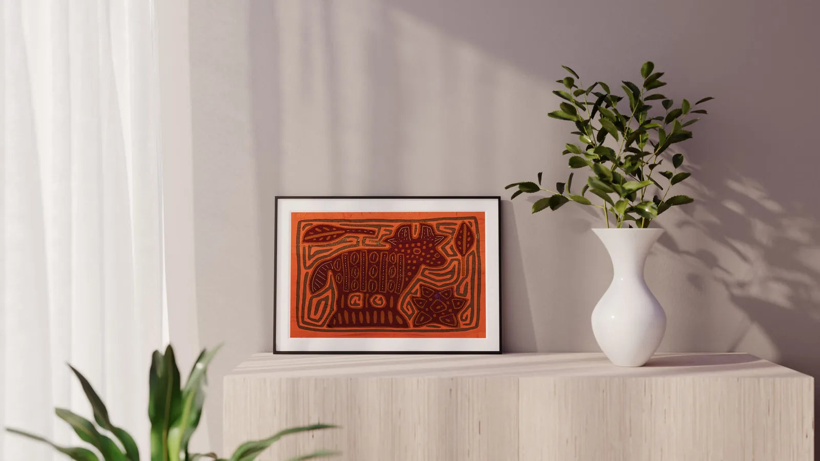 Hand-stitched orange and brown puppy Mola tapestry displayed in a modern setting with plants.