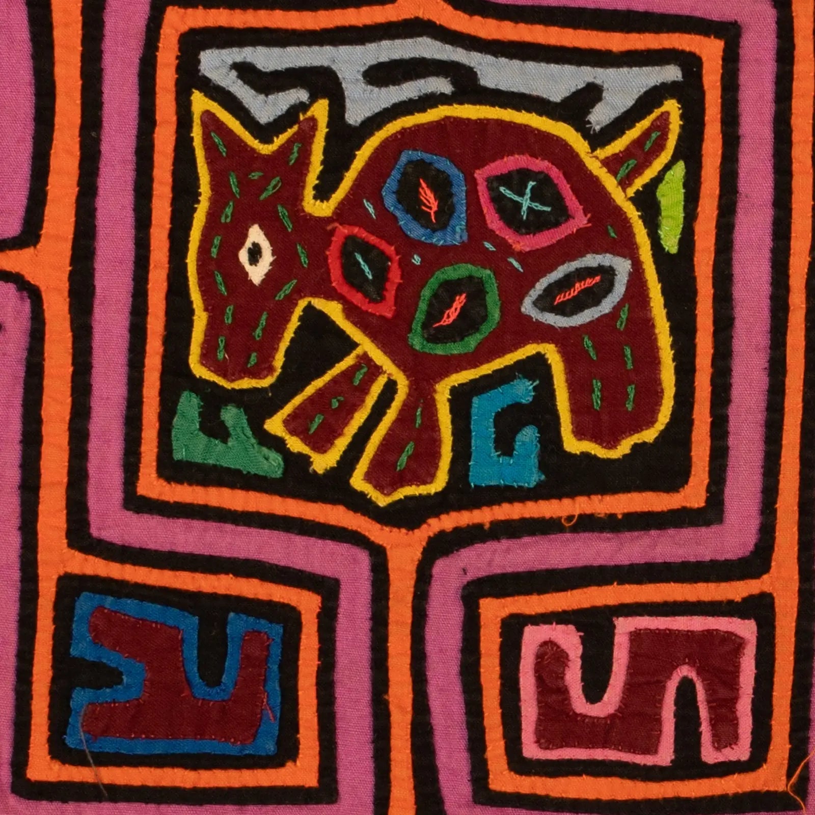Colorful hand-stitched Mola featuring a playful dog design in red and green on a purple background.