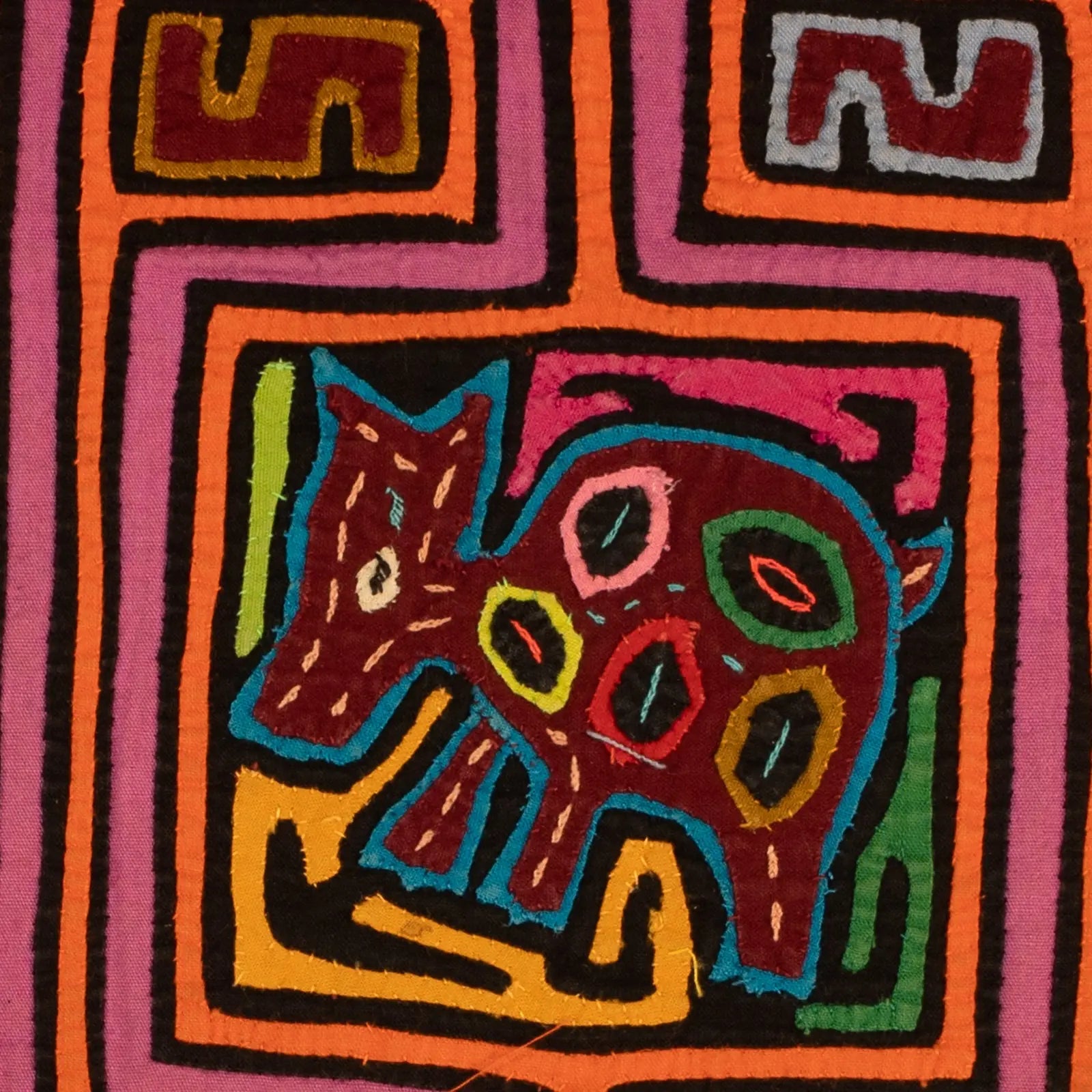 Colorful hand-stitched Mola depicting a playful dog, showcasing bold orange, purple, and black patterns.
