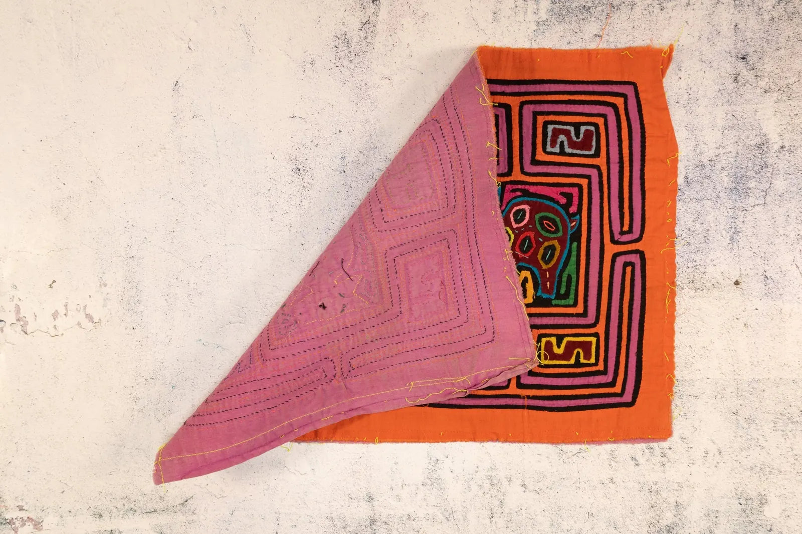 Hand-stitched orange and purple Mola tapestry featuring vibrant abstract designs and textured fabric.