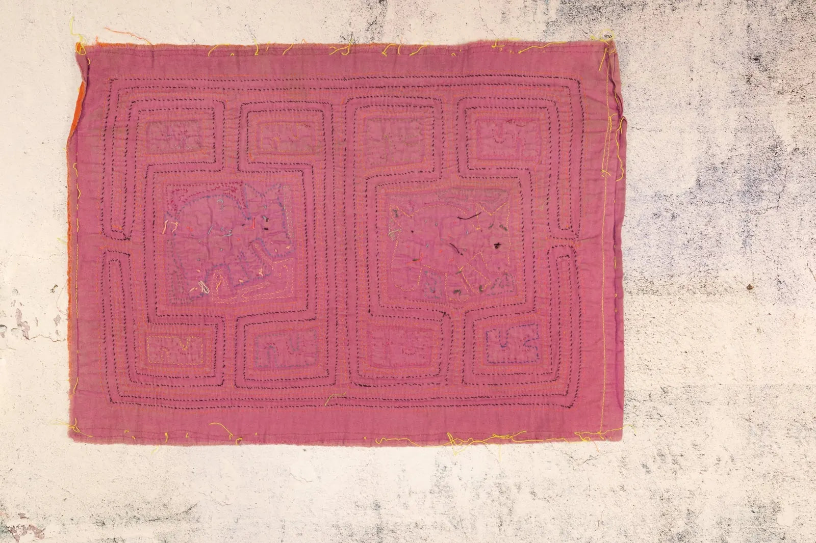 Hand-stitched orange and purple Mola textile art with geometric patterns, made by Guna artisans in Panama.
