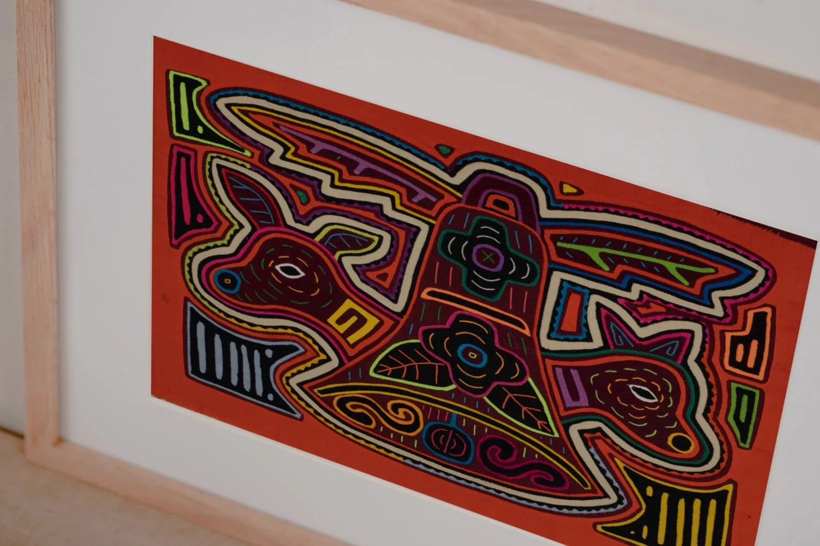 Colorful hand-stitched Mola tapestry featuring an orange and white puppy design with intricate layered patterns.