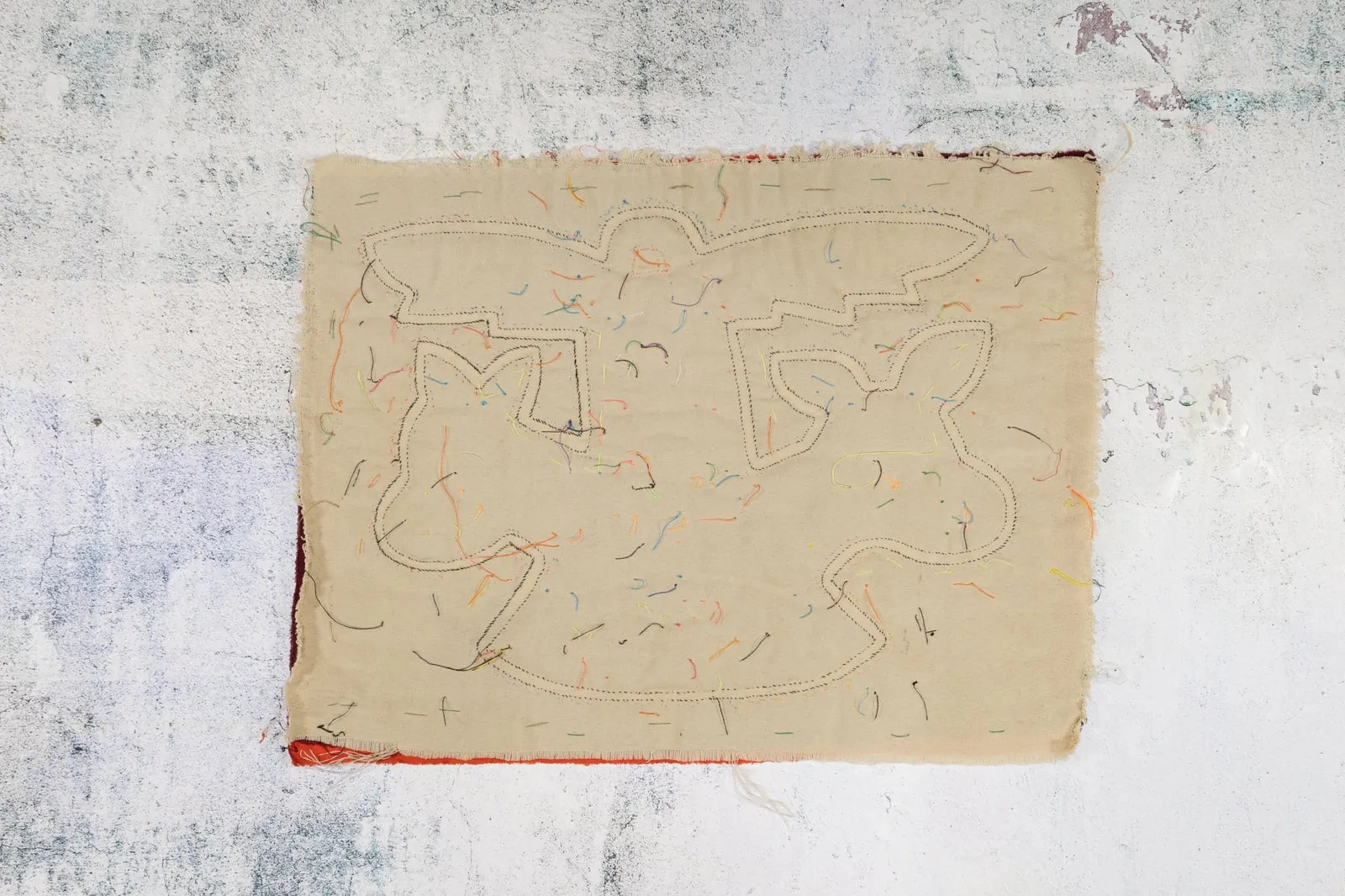 Hand-stitched orange and white puppy dog design in Mola textile art, with colorful threads on a soft beige background.
