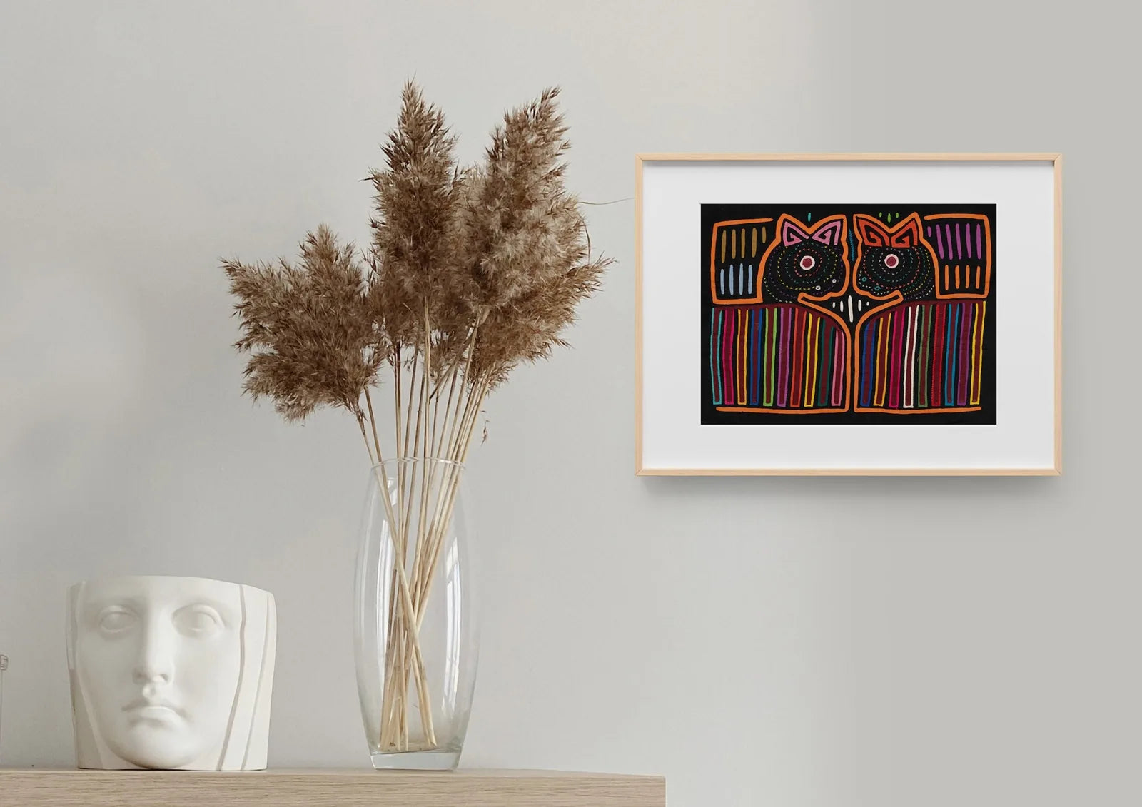 Hand-stitched orange and black Mola tapestry featuring two stylized puppy faces with vibrant geometric patterns.