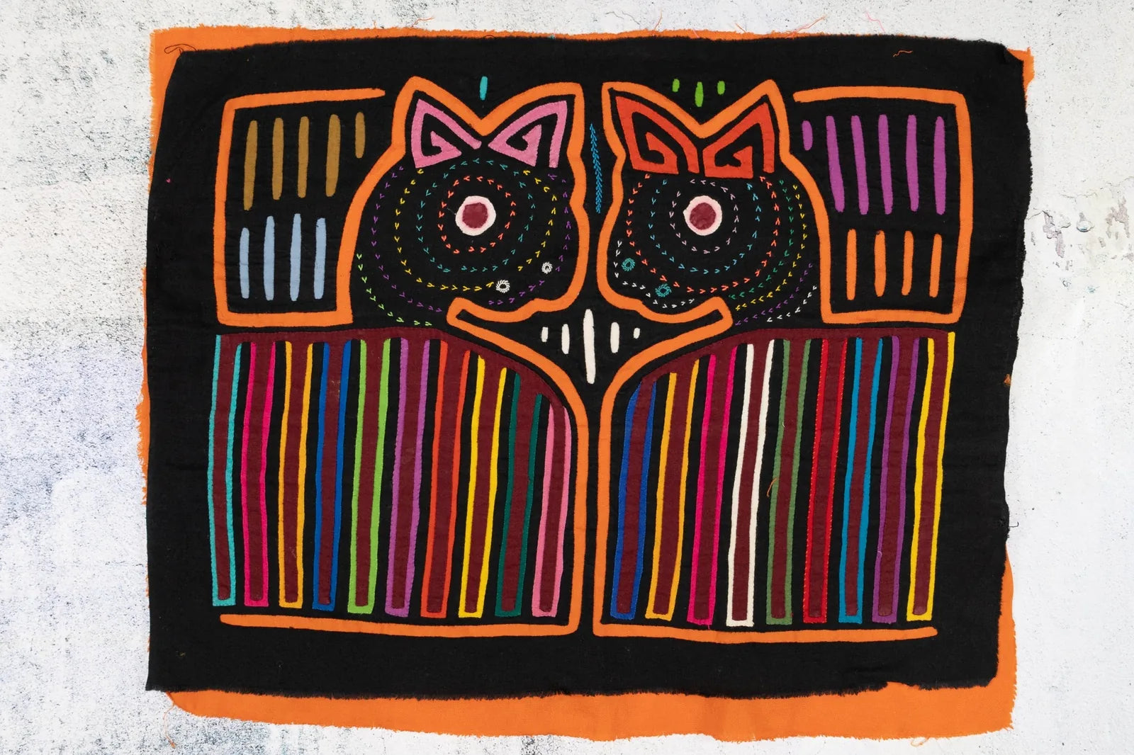 Hand-stitched orange puppy dog Mola tapestry with vibrant geometric patterns on a black background, showcasing indigenous...