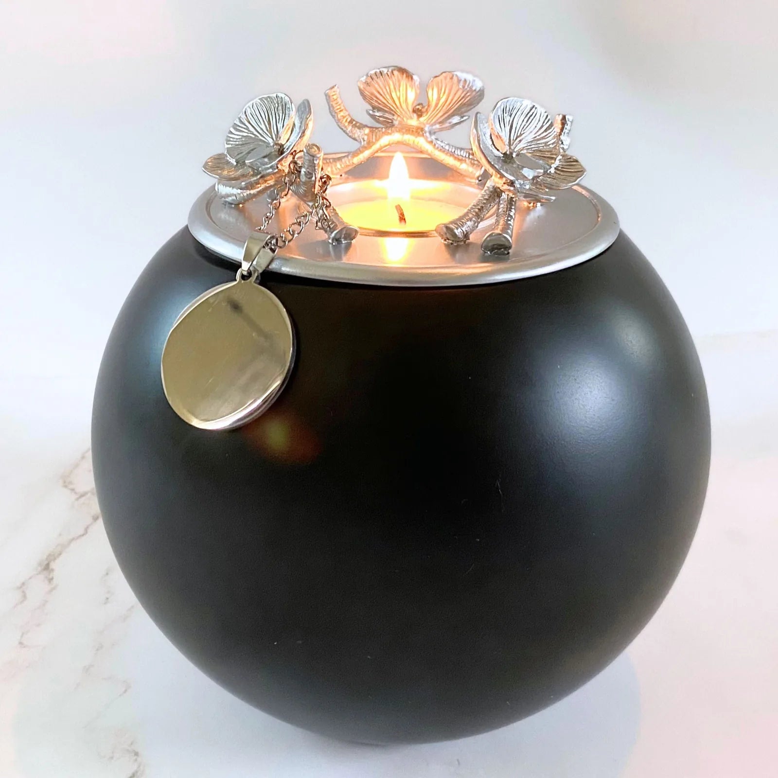 Handmade black Orchid Urn with silver floral lid and attached metal tag for pet ashes, designed for home display.