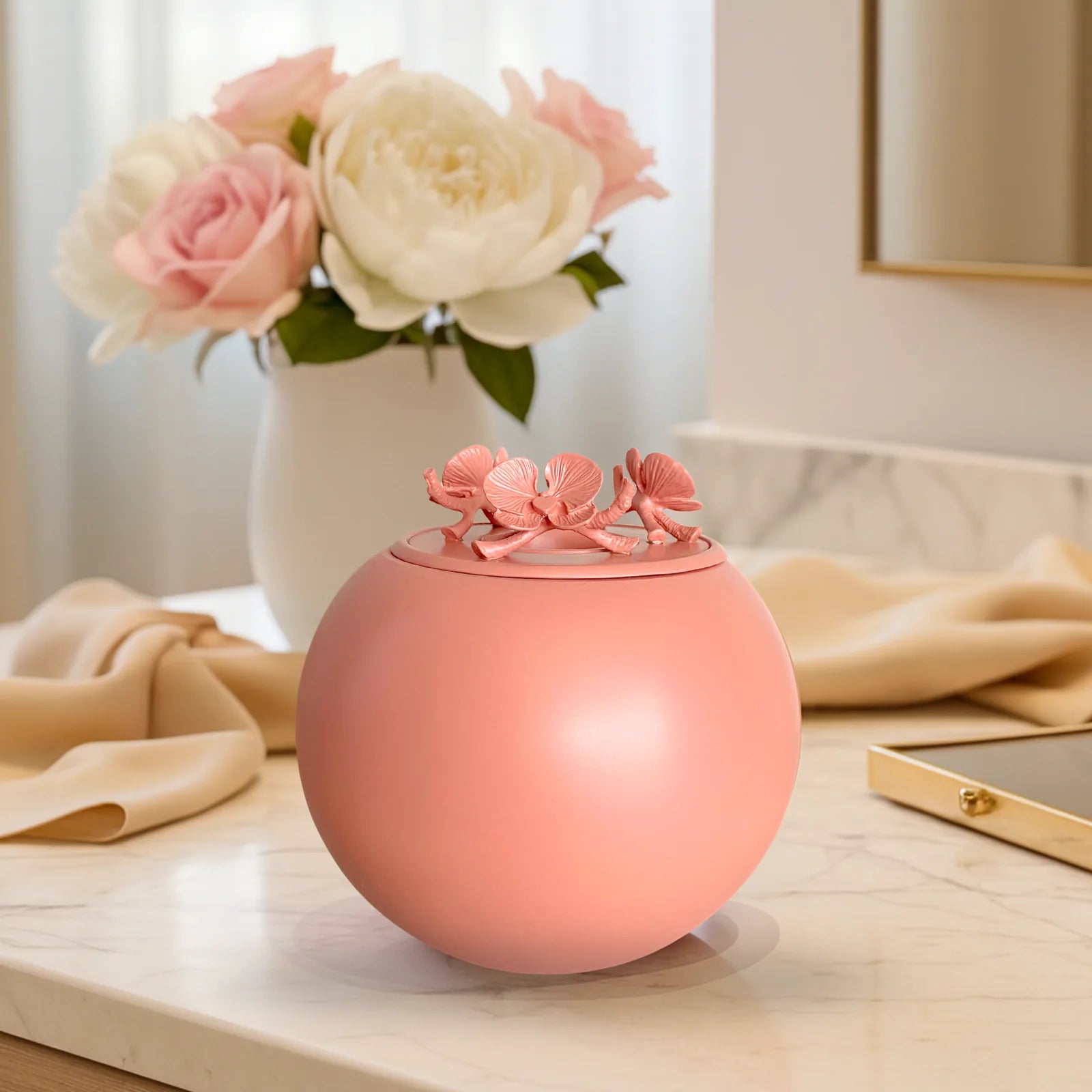 Coral Orchid Urn with flower detail, set on a marble surface beside soft fabric and flowers, perfect for pet ashes.