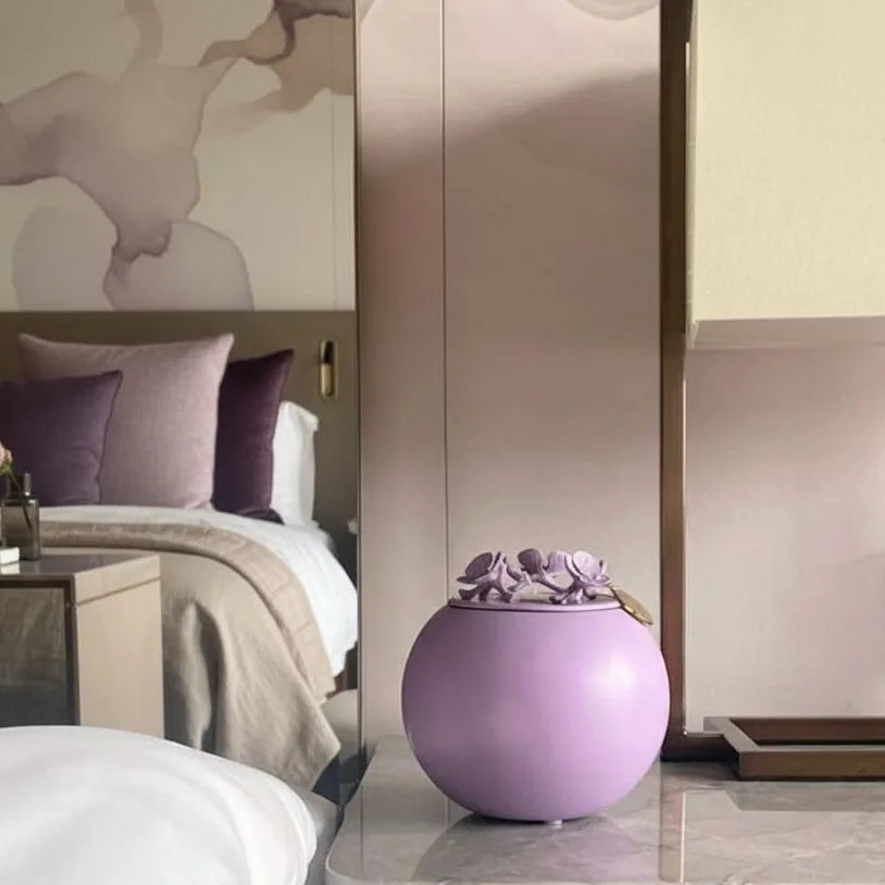 Handmade lavender orchid urn for pet ashes, elegantly displayed in a serene bedroom setting.