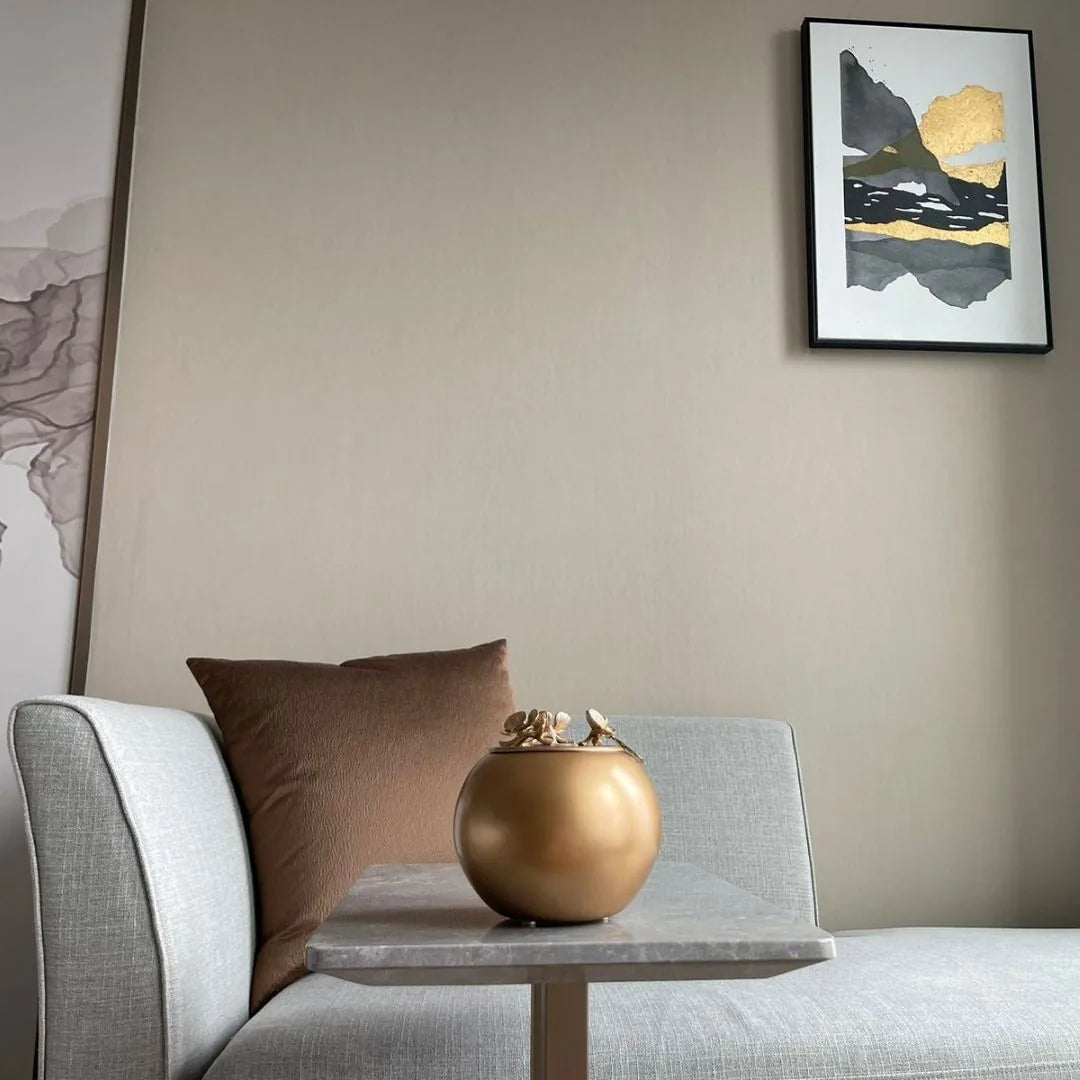 Handcrafted gold Orchid Urn on a modern gray table, featuring a contemporary design and elegant keepsake size.