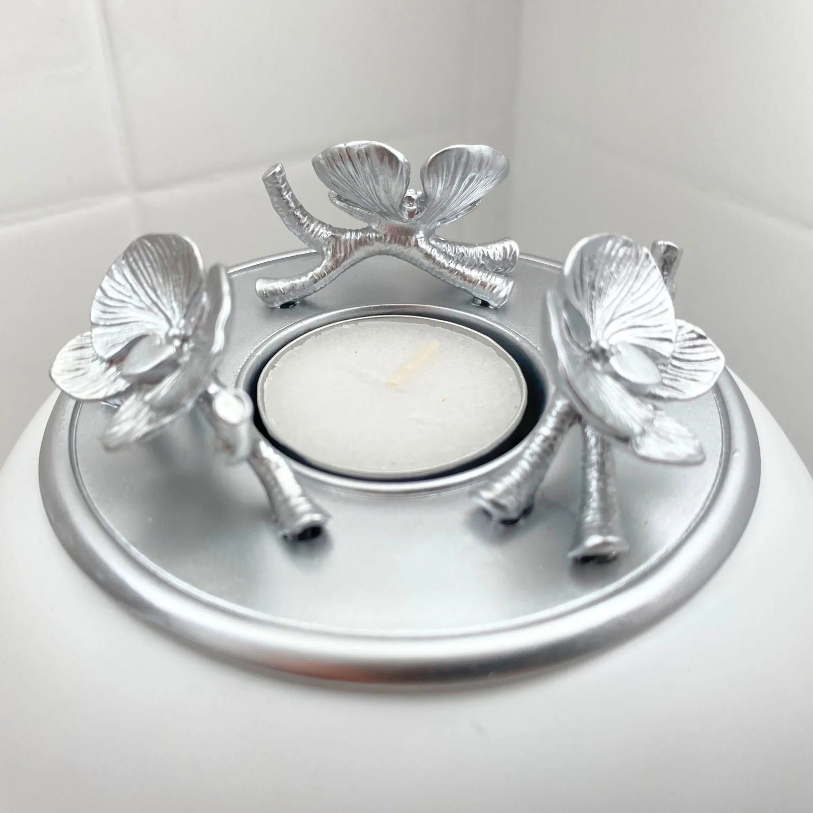 Orchid urn with a silver flower design and candle holder, featuring a white base and intricate handcrafted details.