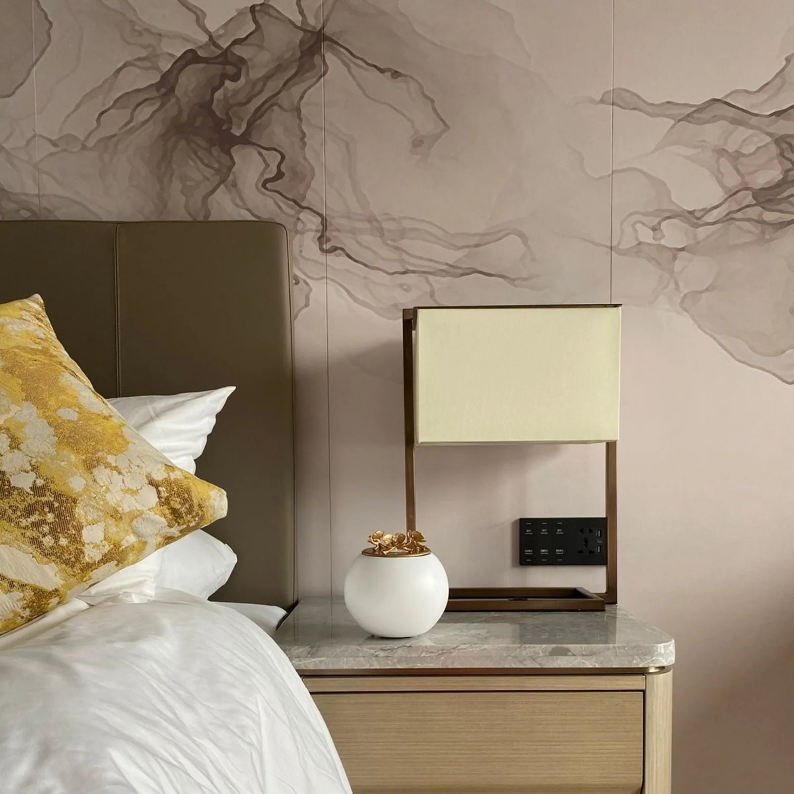 Handmade white ceramic orchid urn with a gold lid, elegantly displayed on a bedside table beside a decorative lamp.