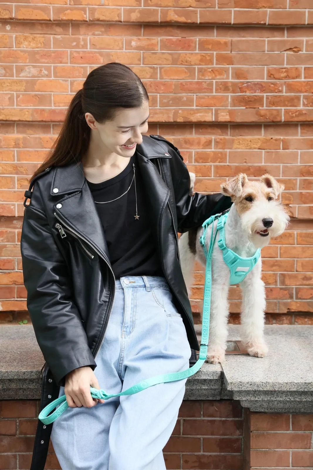 Padded active pet leash in apricot, held by a person with a black leather jacket and light blue jeans, alongside a dog.