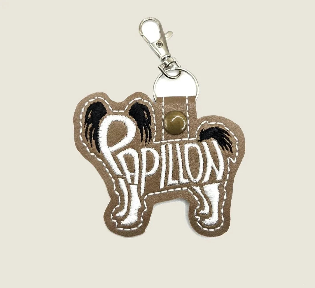 Embroidered Papillon dog keychain in brown felt with black detailing and silver swivel clasp, perfect for dog lovers.