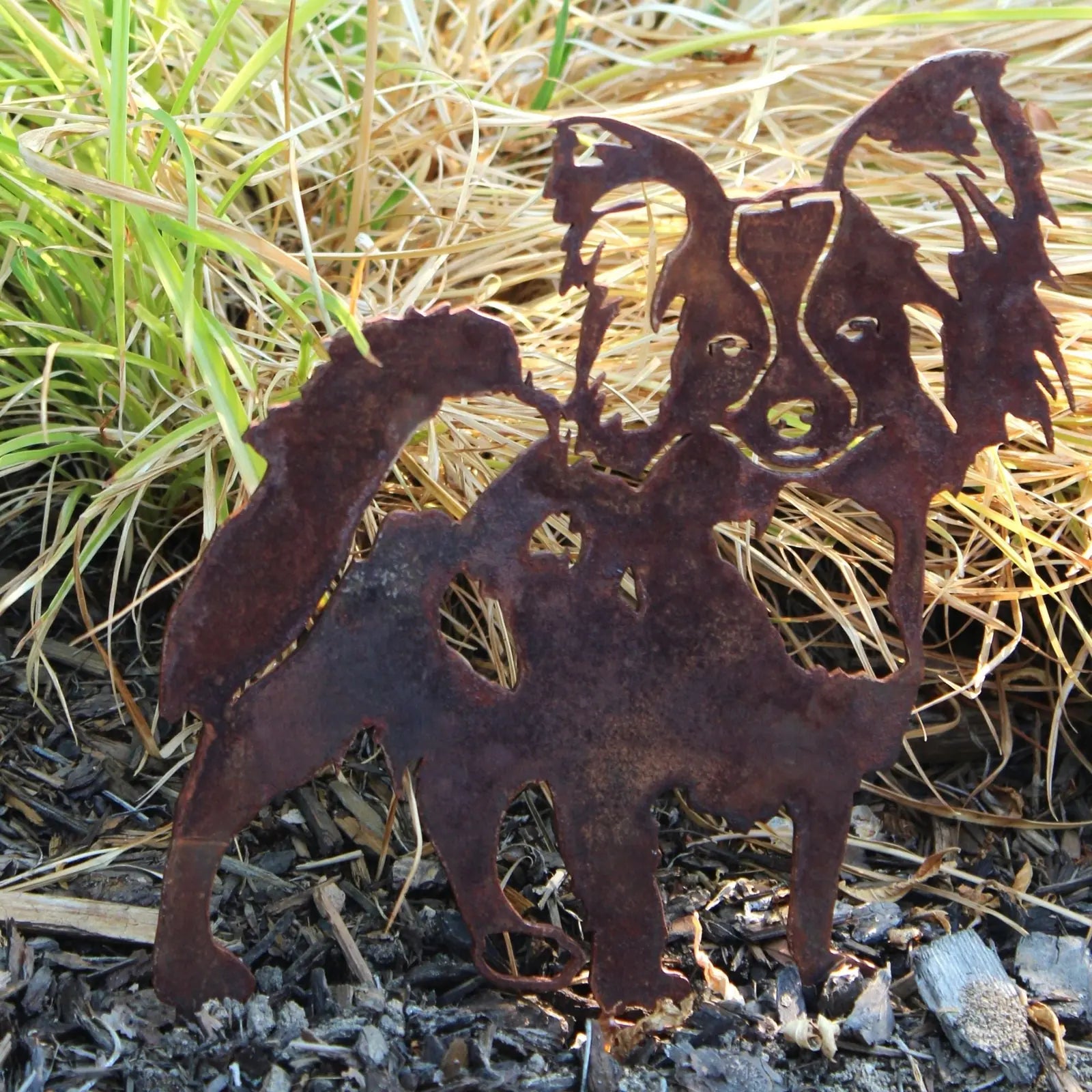 Rusty Corten steel Papillon silhouette garden decor with artistic detailing, set against dry grass and mulch.