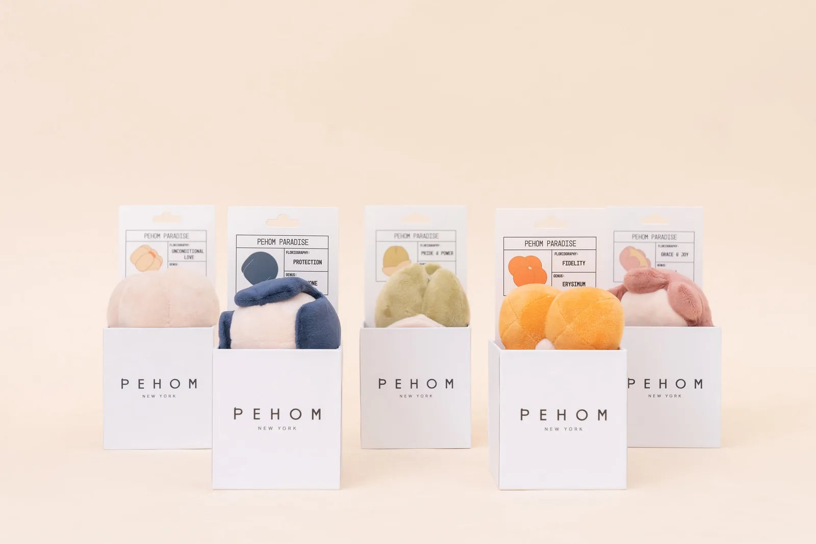 Plush dog toys in various colors, displayed in stylish boxes labeled with playful names and flairs.