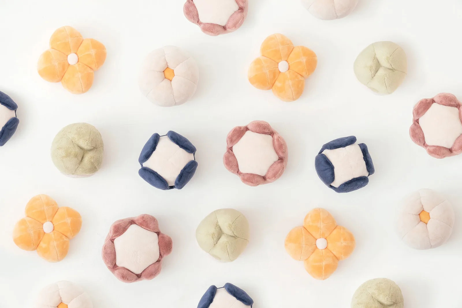 Colorful plush dog toys shaped like flowers and round cushions, designed for interactive play.