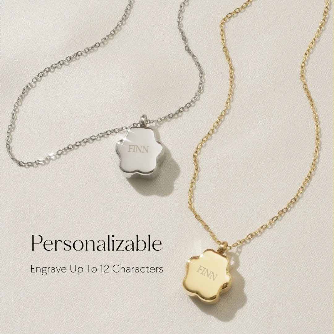 Delicate silver and gold cremation necklaces with paw print charms, engraved with the name "FINN," on a soft background.
