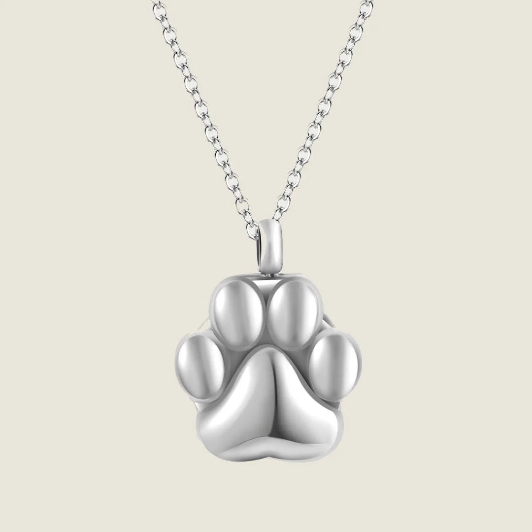 Silver paw print cremation necklace on a delicate chain, designed to hold pet ashes or a lock of hair.