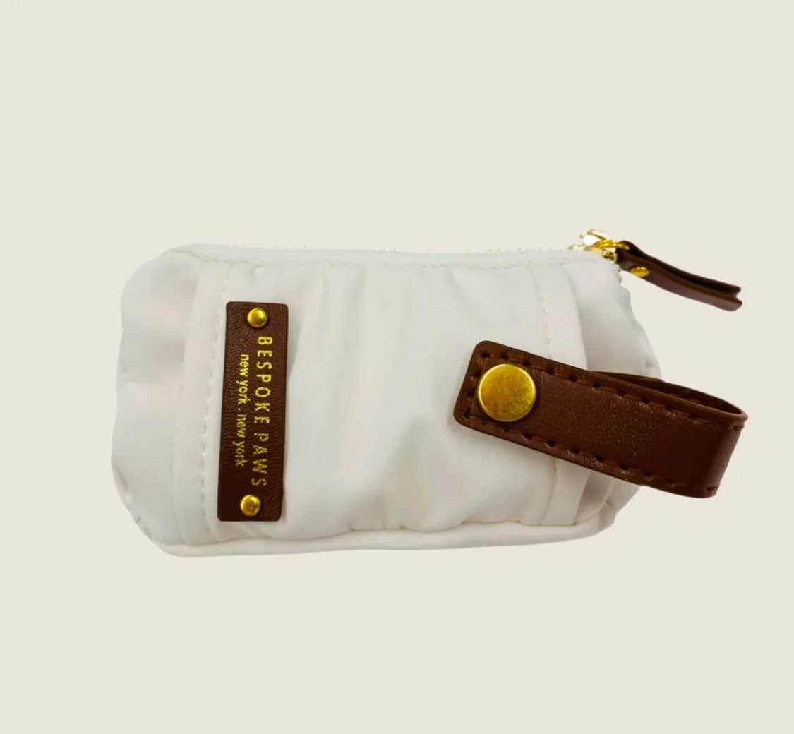 Ivory waste bag dispenser with brown vegan leather accents and gold zipper, featuring "BESPOKE PAWS" branding.