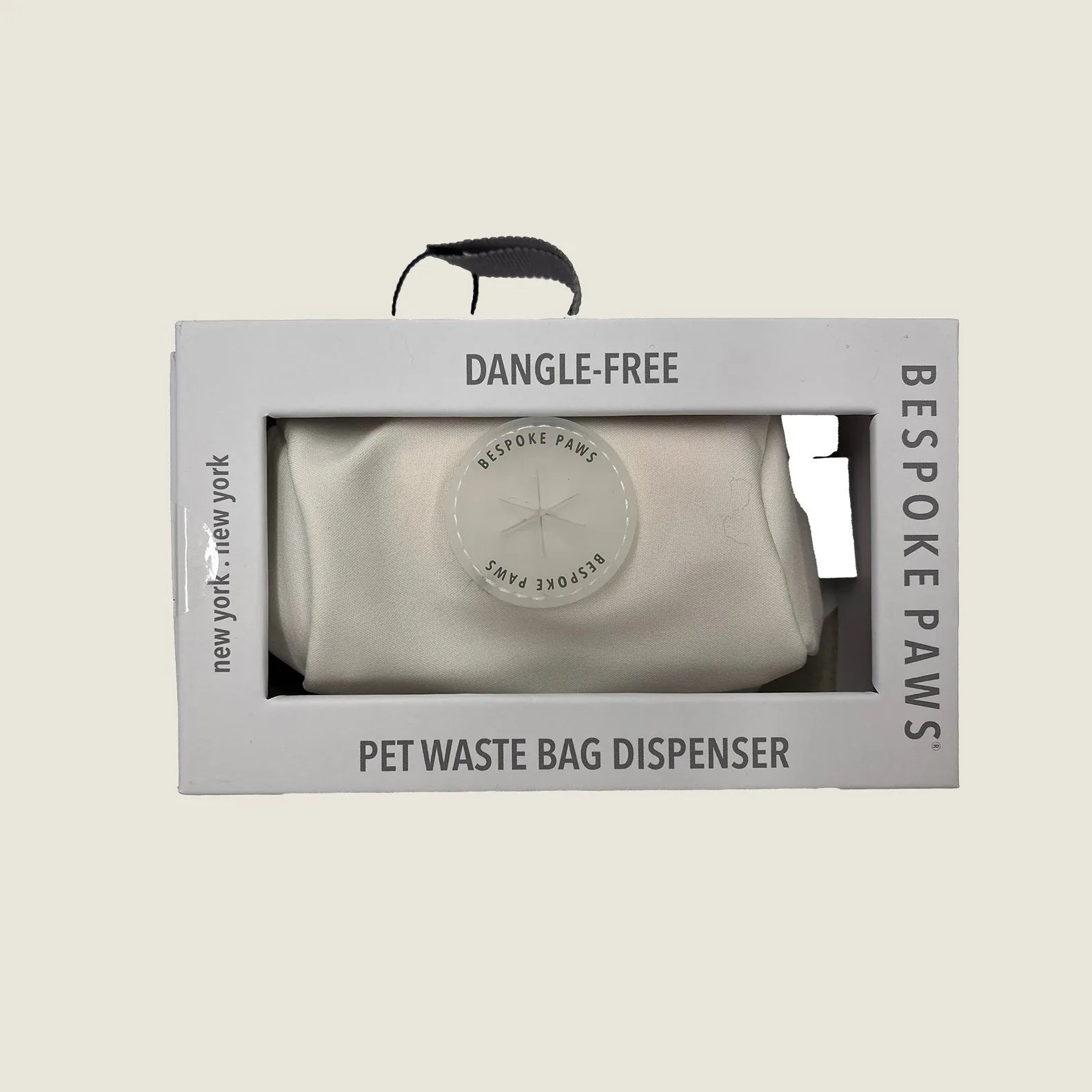 Sleek ivory waste bag dispenser in packaging, featuring Bespoke Paws branding and a dangle-free design.
