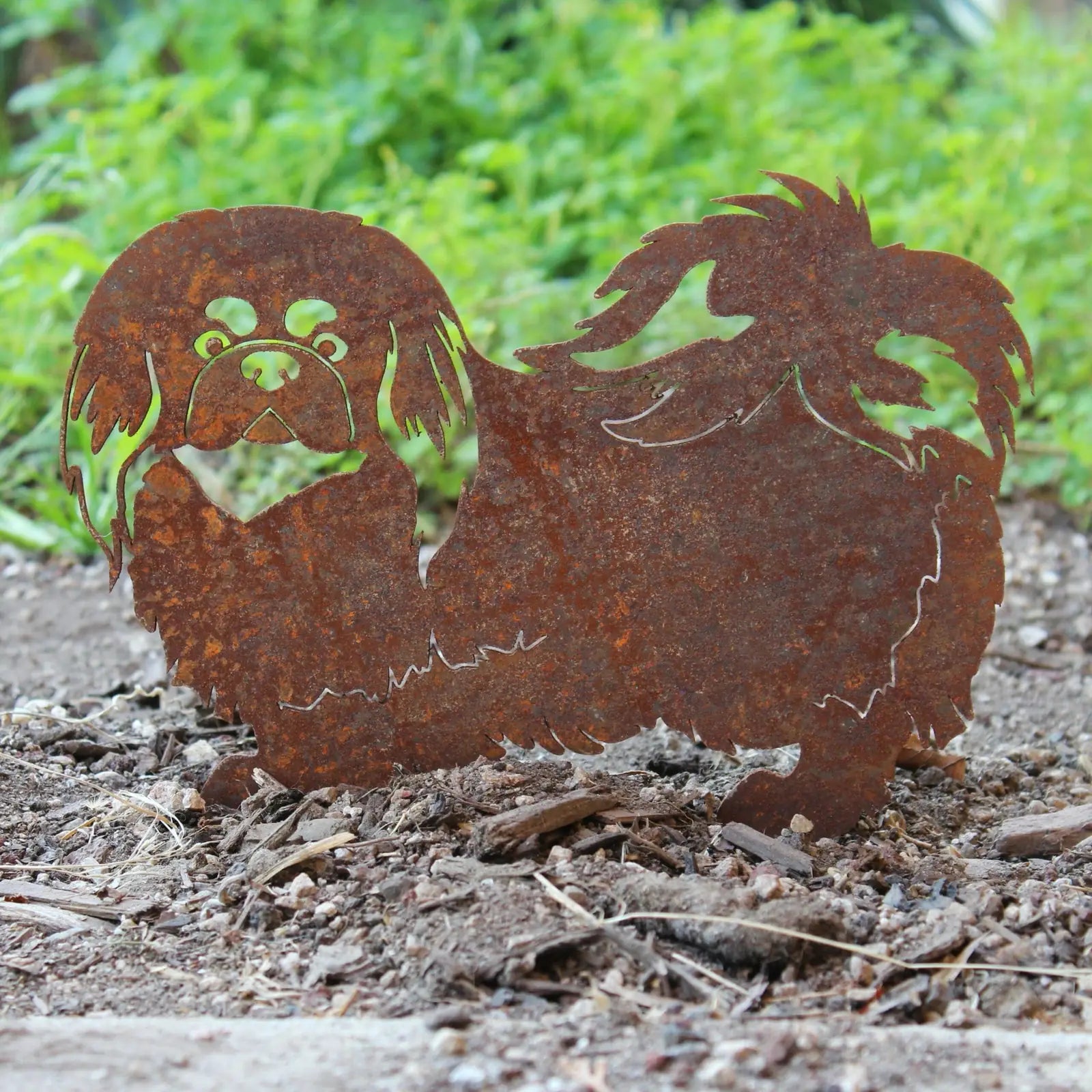 Pekingese metal silhouette in rusted Corten steel, showcasing intricate fur details against a natural background.