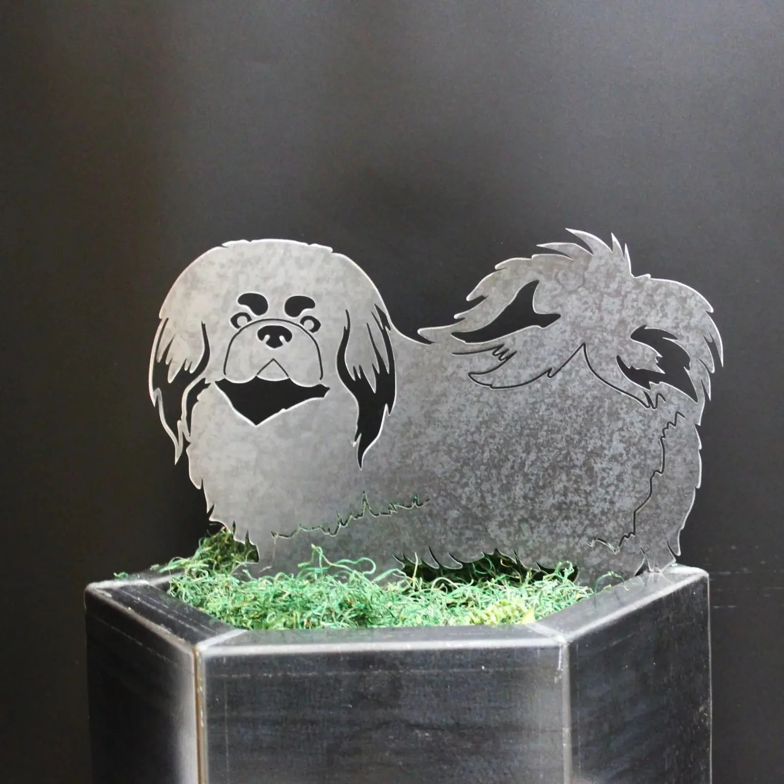 Pekingese metal silhouette art in gray, showcasing detailed hair and features, set against a dark background.