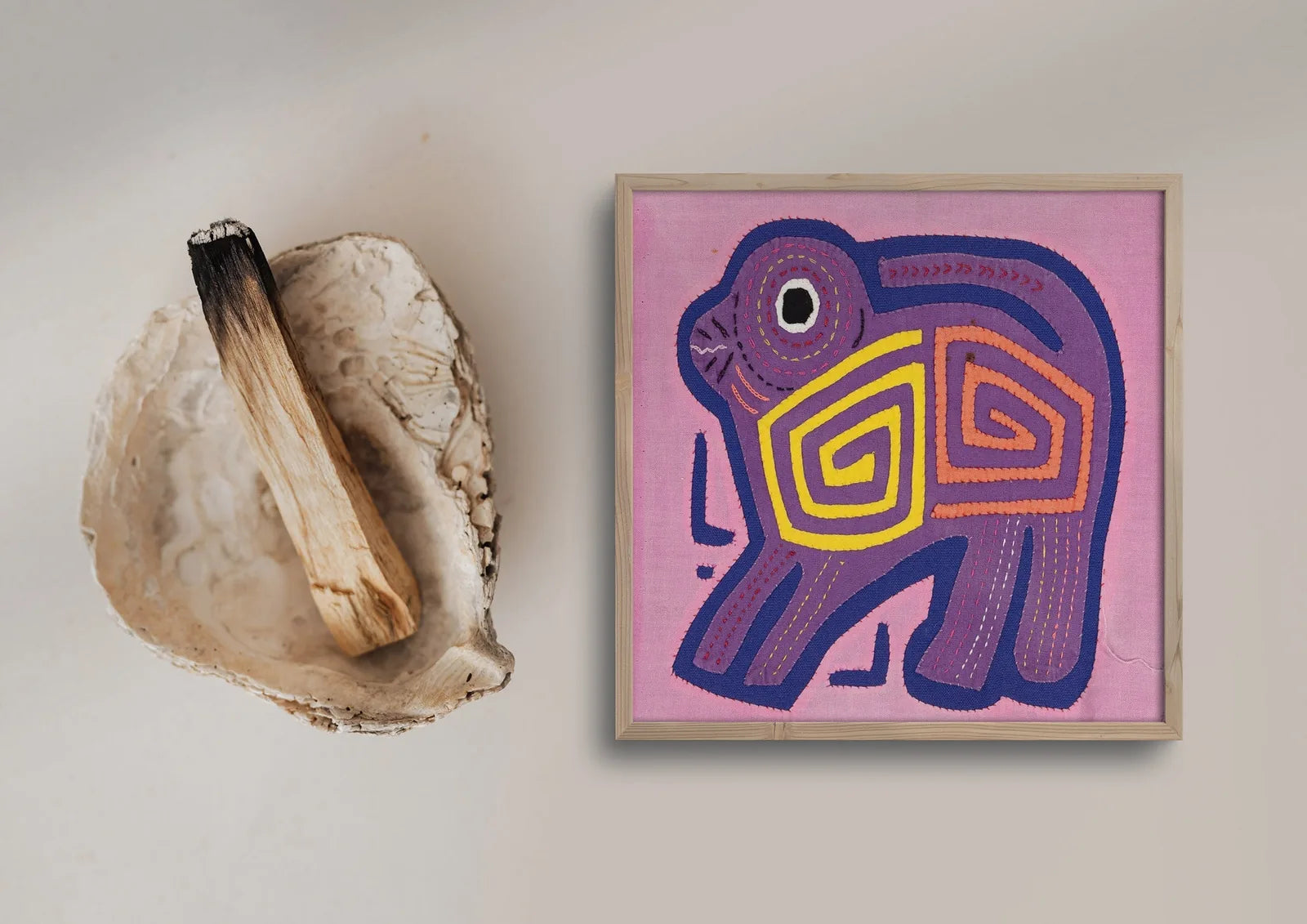 Hand-stitched pink and purple Mola depicting a playful puppy dog with geometric patterns on a vibrant background.