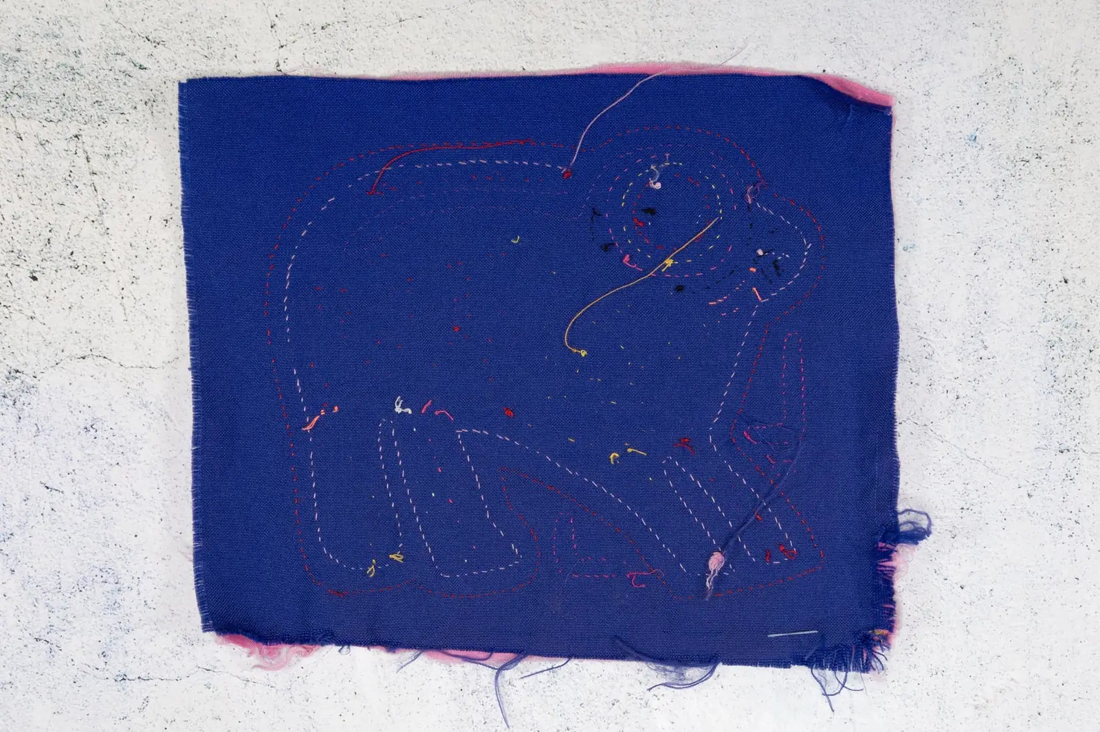 Hand-stitched purple fabric featuring a playful puppy design with multicolored stitching, showcasing Latin American textil...