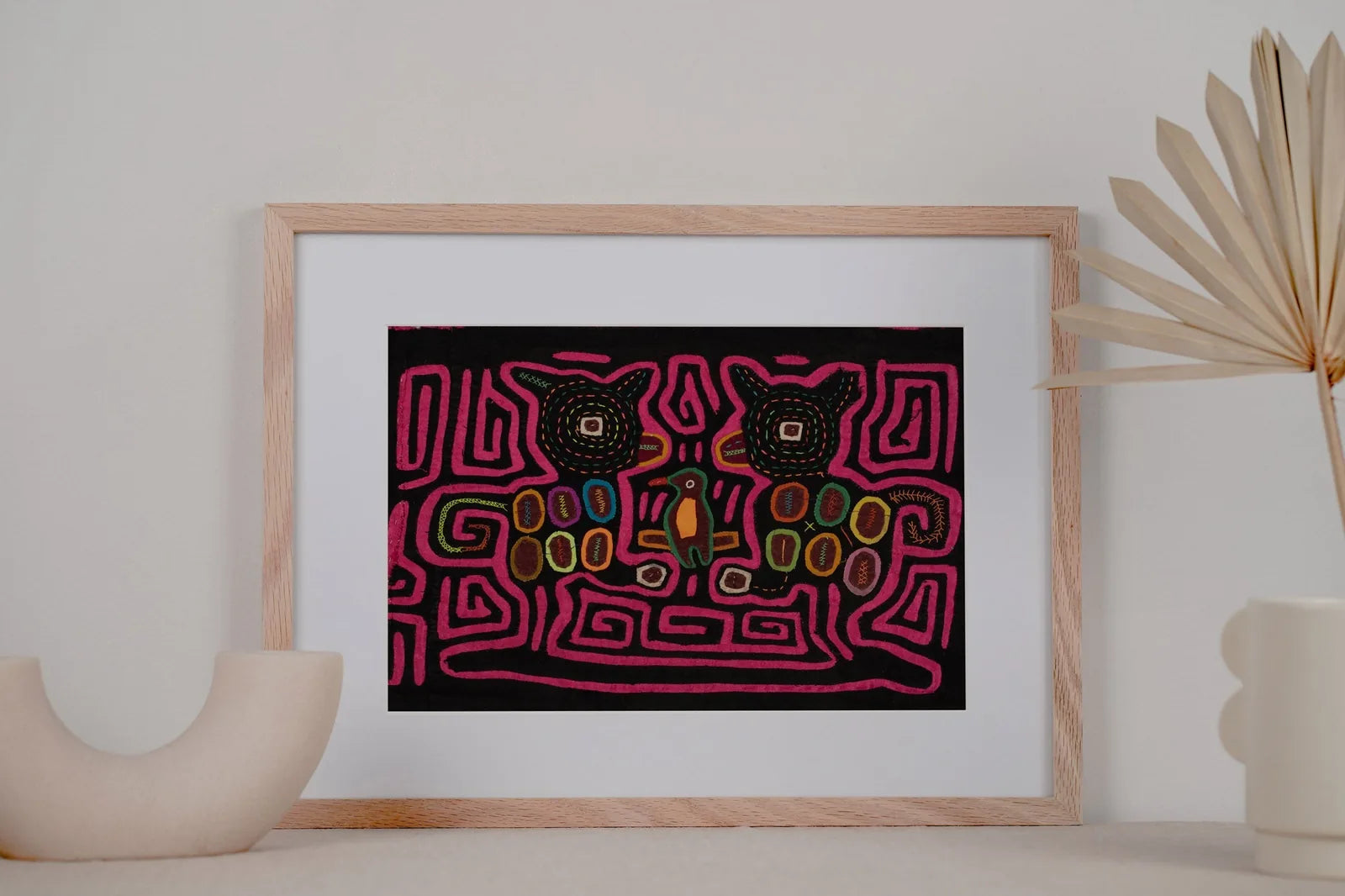 Hand-stitched Panama Mola with vibrant pink, green, and brown geometric designs featuring animals on a black background.
