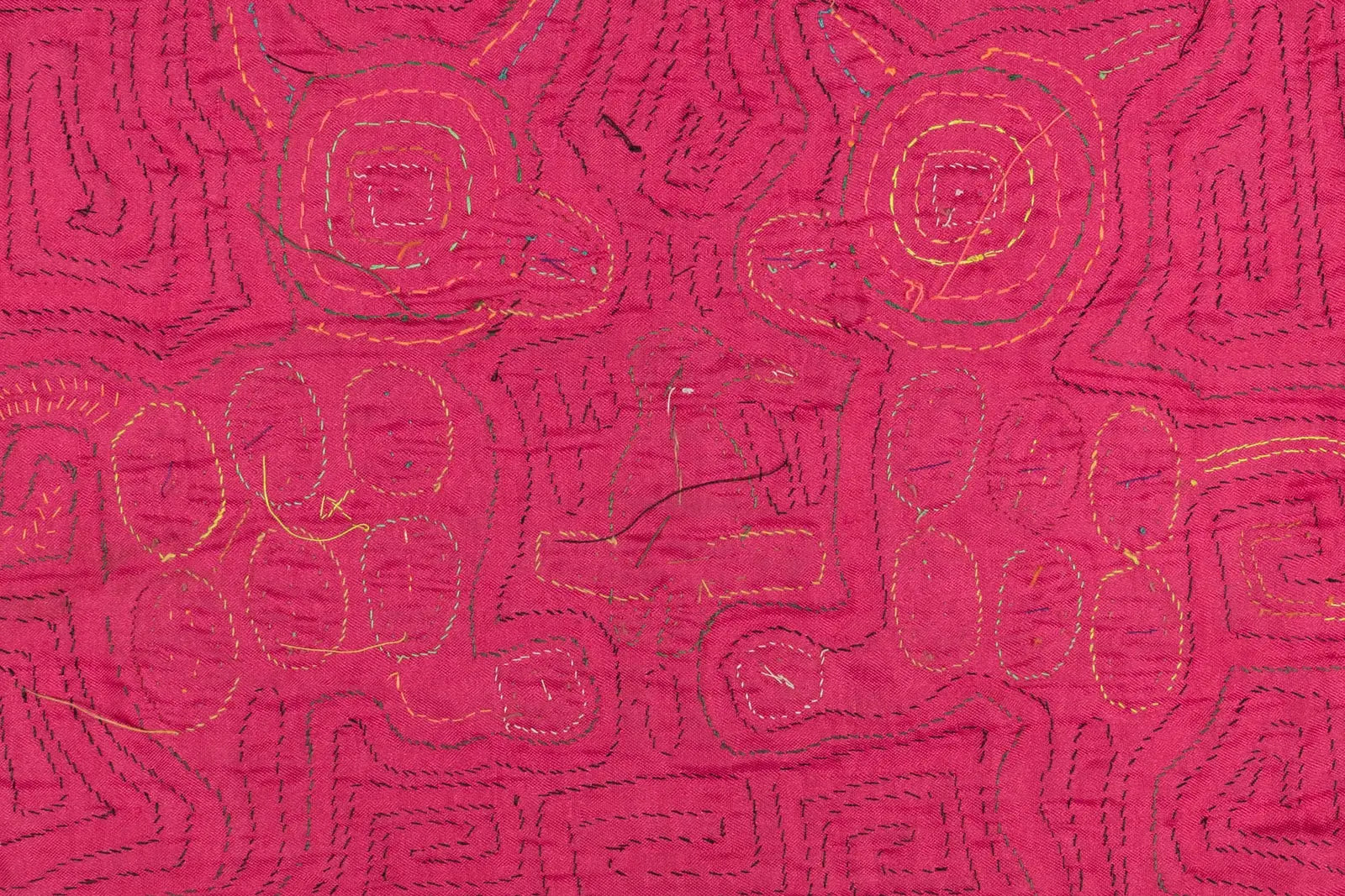 Hand-stitched pink Mola textile featuring colorful geometric patterns on a vibrant background.