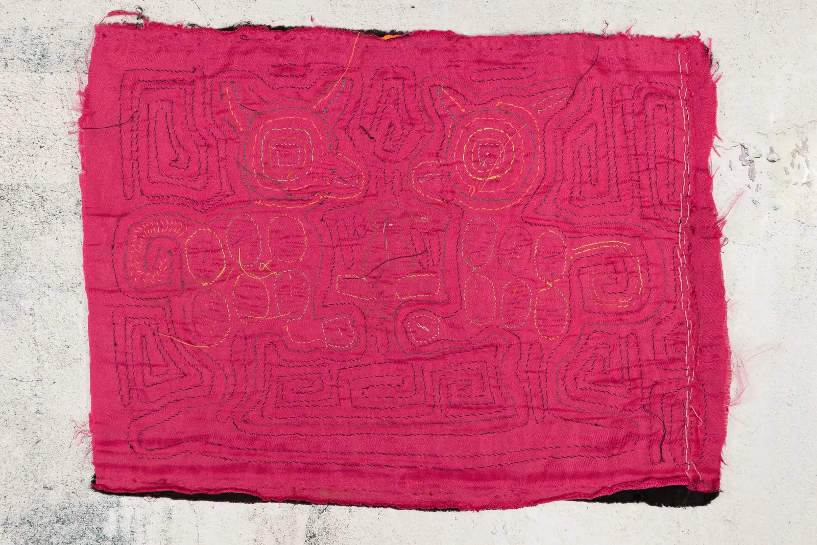 Hand-stitched pink Mola textile featuring geometric designs in contrasting thread, celebrating Guna artistry.