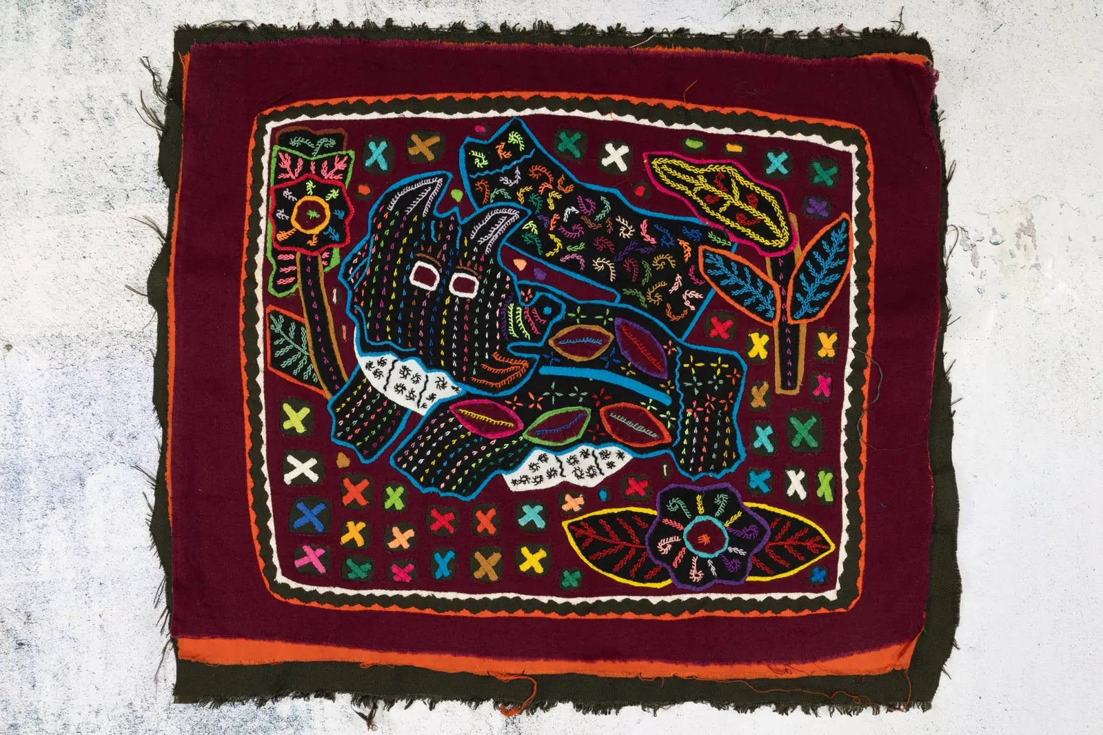 Colorful hand-stitched Mola featuring a playful terrier puppy with geometric patterns and vibrant floral designs.